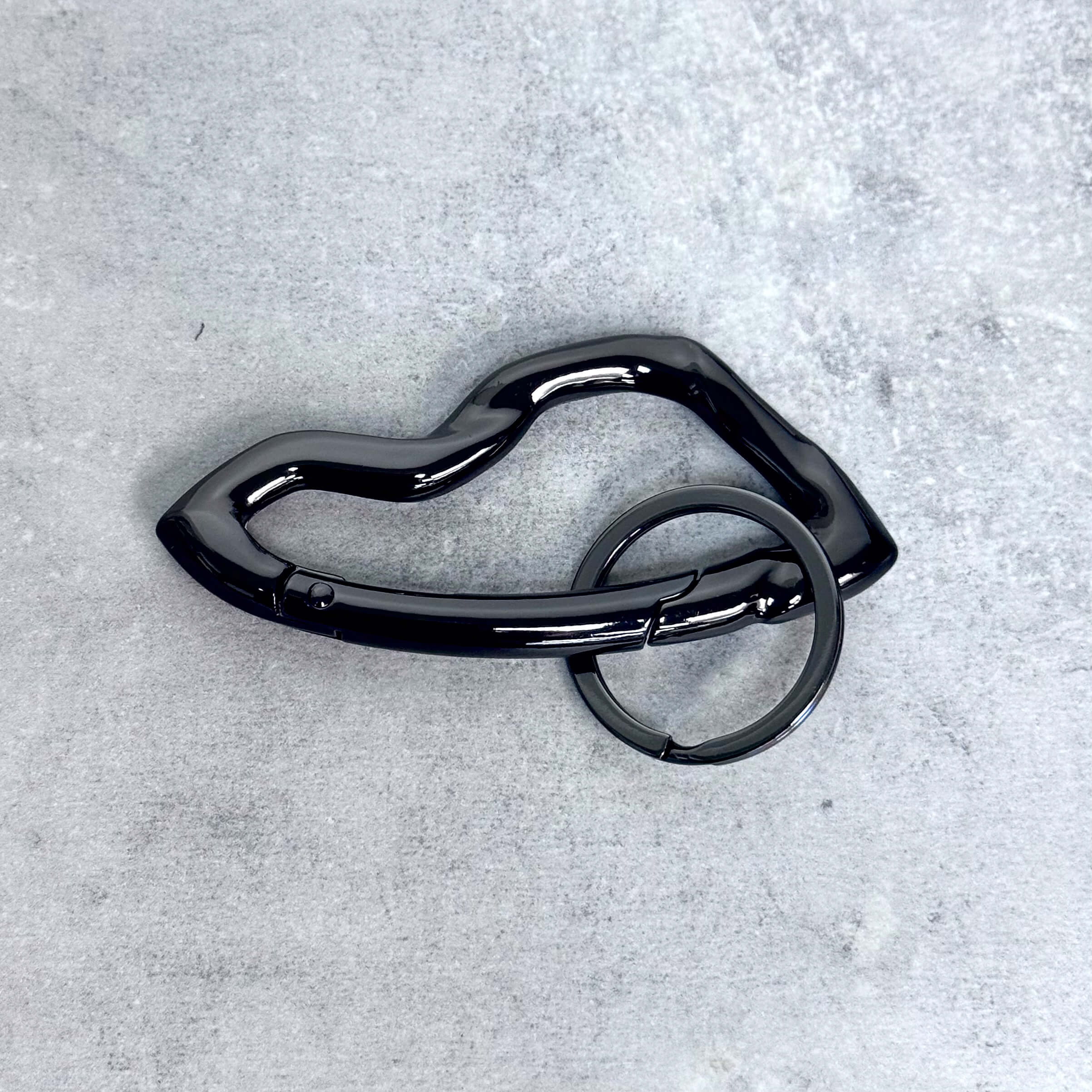 Glossy black Irregular Y2K carabiner keychain with fluid wavy frame and matching dark metal key ring.