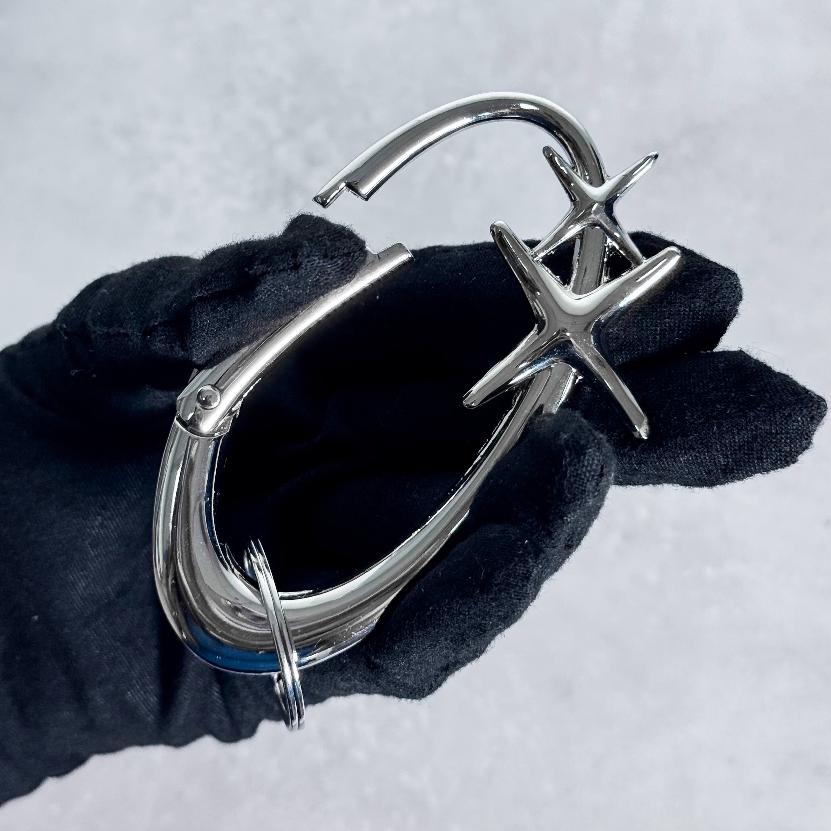 Close-up of silver Starlight Y2K Carabiner Keychain with dual star design held in gloved hand.