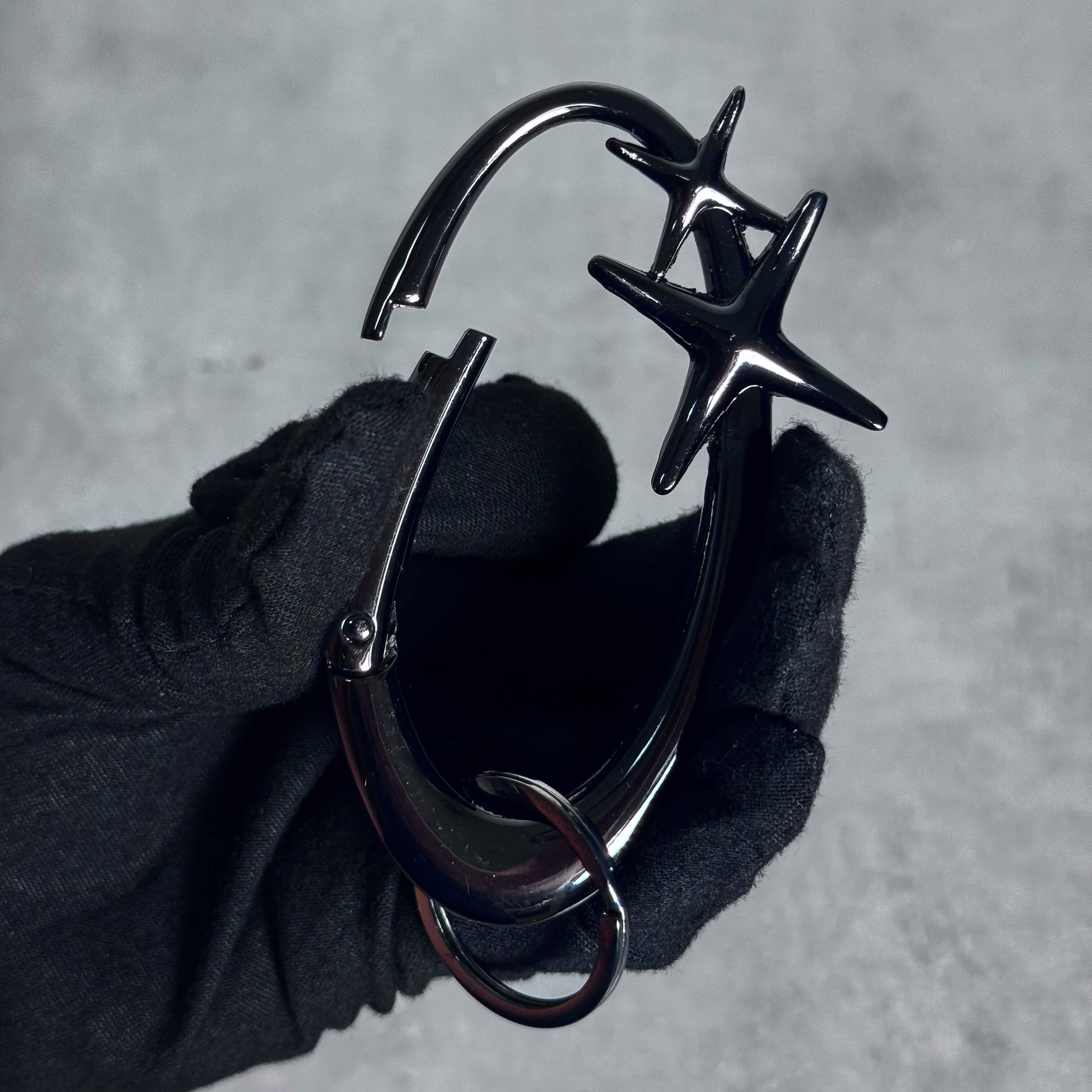 Close-up of black Starlight Y2K Carabiner Keychain with dual star design held in gloved hand.