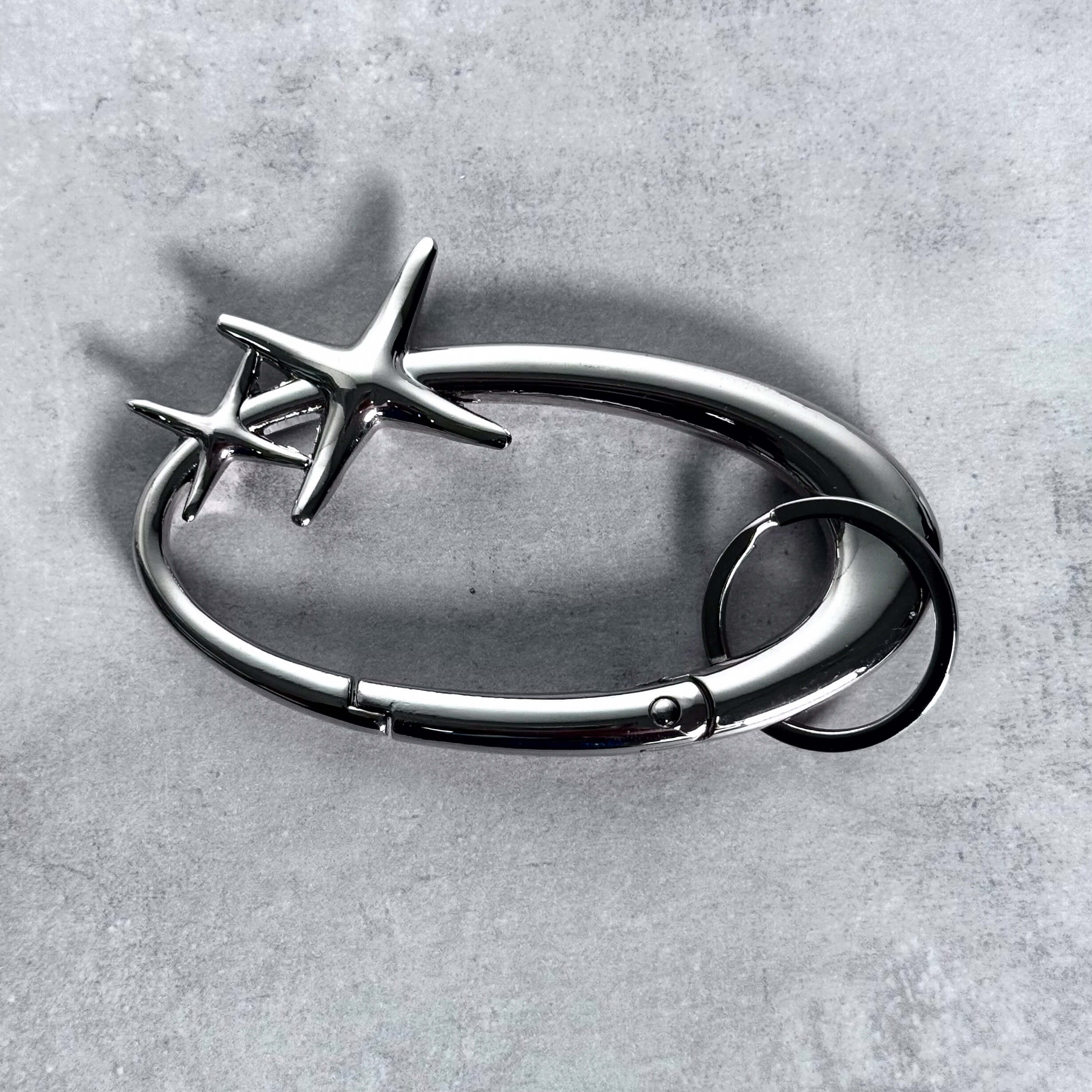 Polished silver Starlight Y2K Carabiner Keychain with star accents displayed on gray surface.