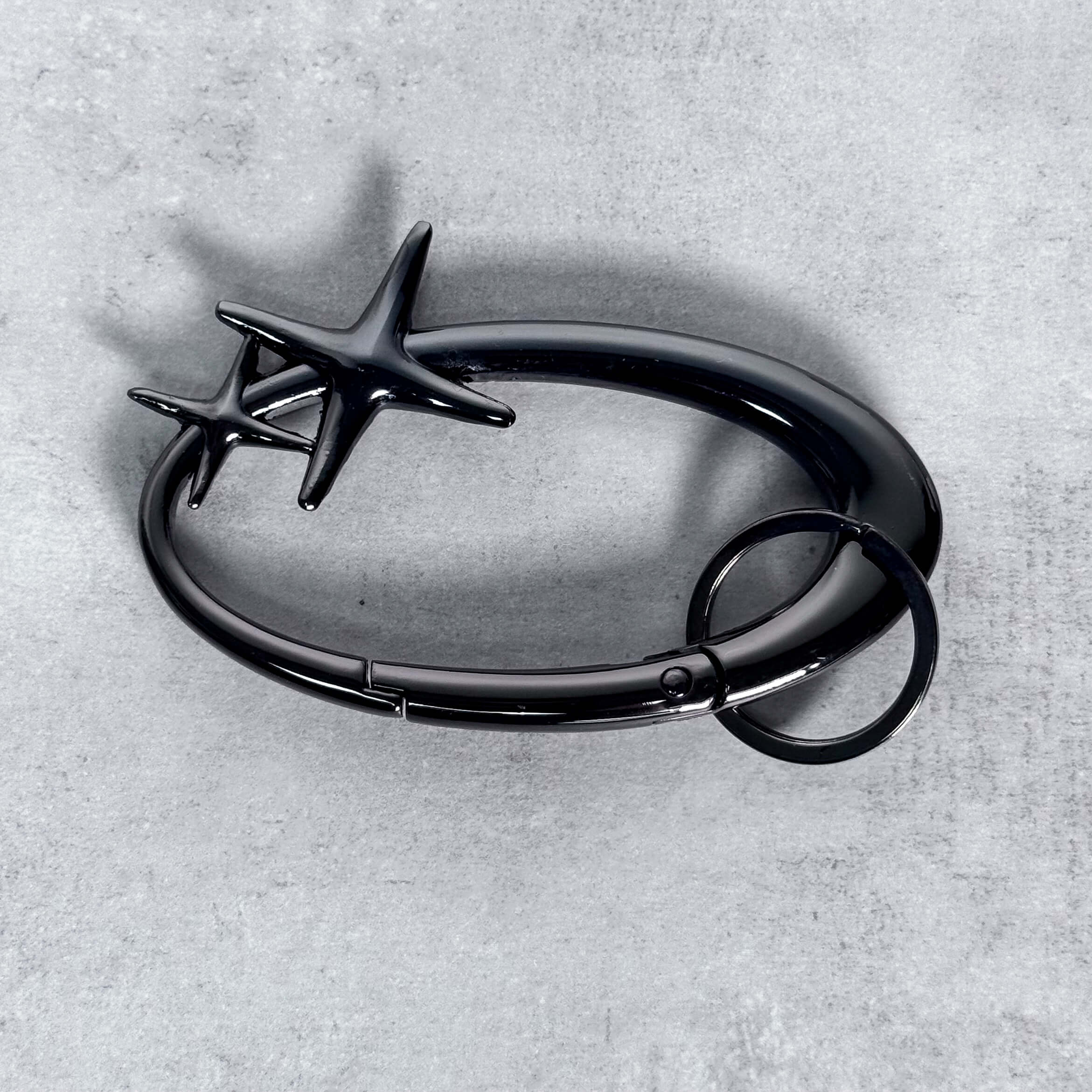 Black Starlight Y2K Carabiner Keychain with star accents displayed on gray surface.