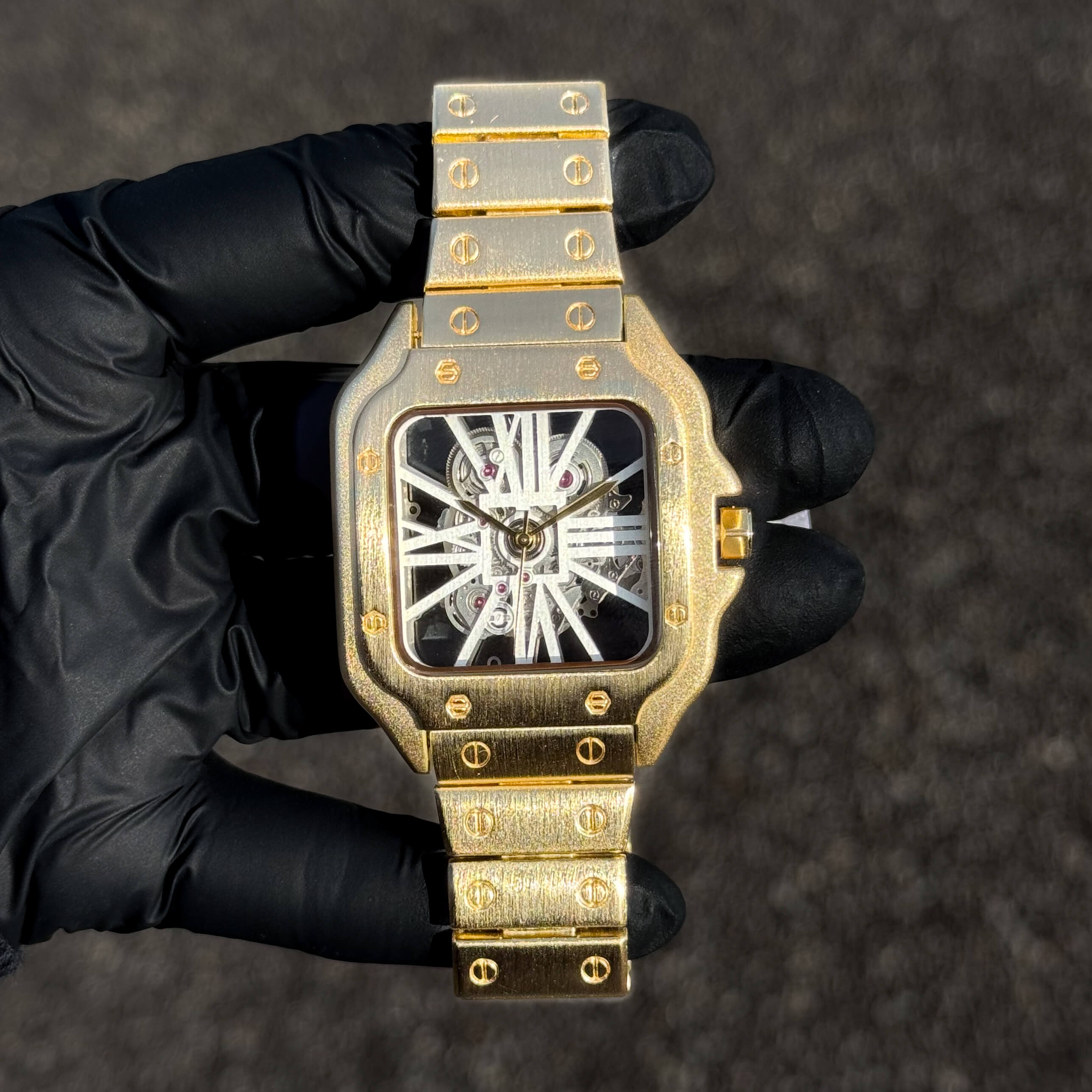 Men's 40mm gold square skeleton dial watch with brushed metal band and exposed movement.