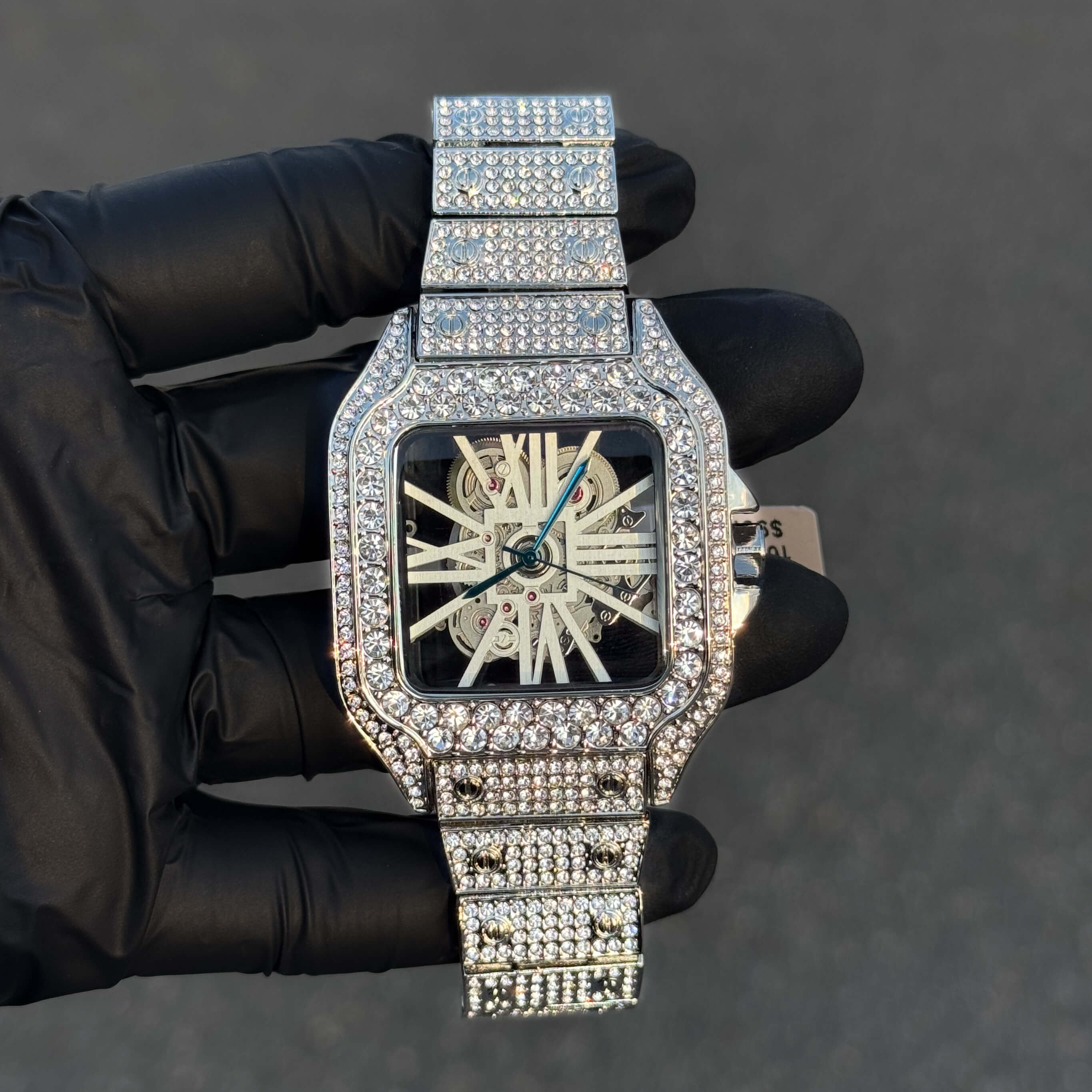 Silver fully iced out 40mm square men’s diamond watch with skeleton dial and steel bracelet.