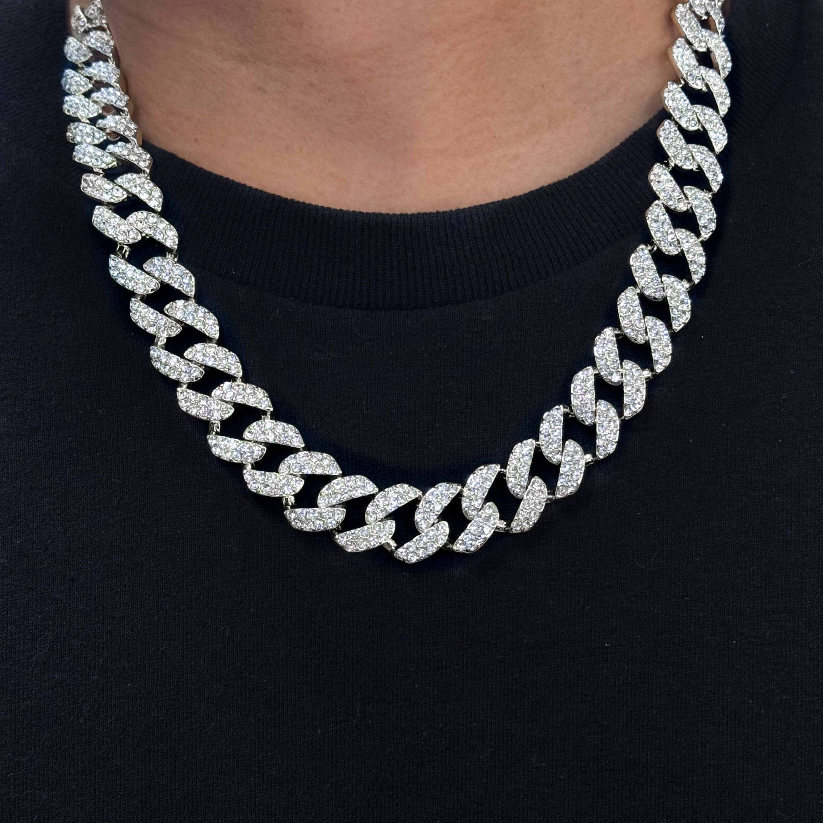 15mm Iced Out Cuban Chain in silver with pavé CZ stones, worn close-up around neck against black shirt.