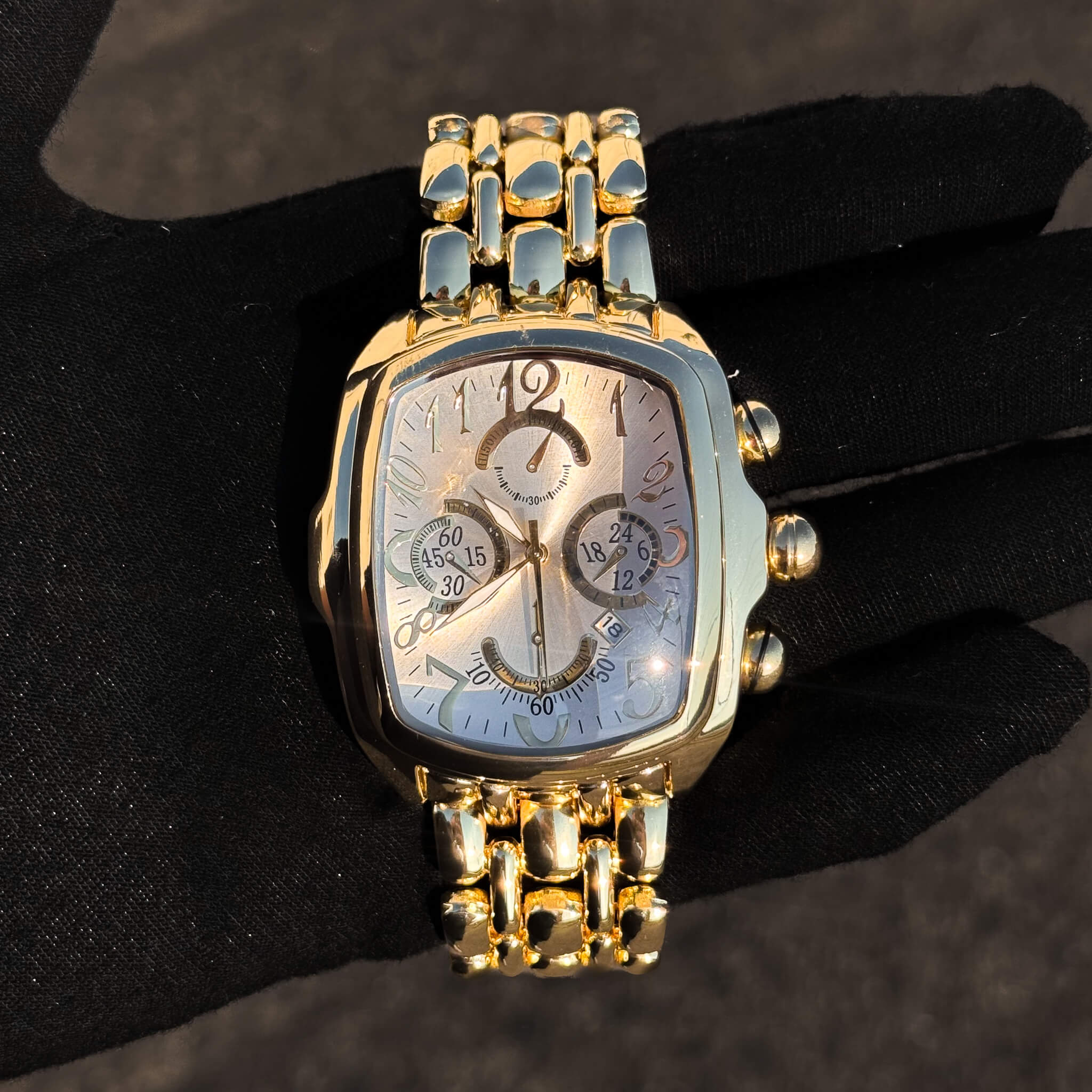 Men’s 43mm tonneau watch with gold case, silver chronograph dial, and luxury metal bracelet.