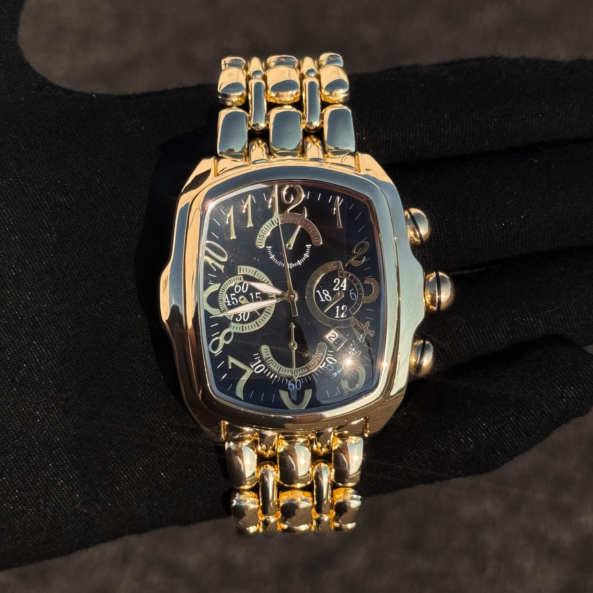 Men’s 43mm tonneau watch featuring a black multi-dial face and gold stainless steel band.