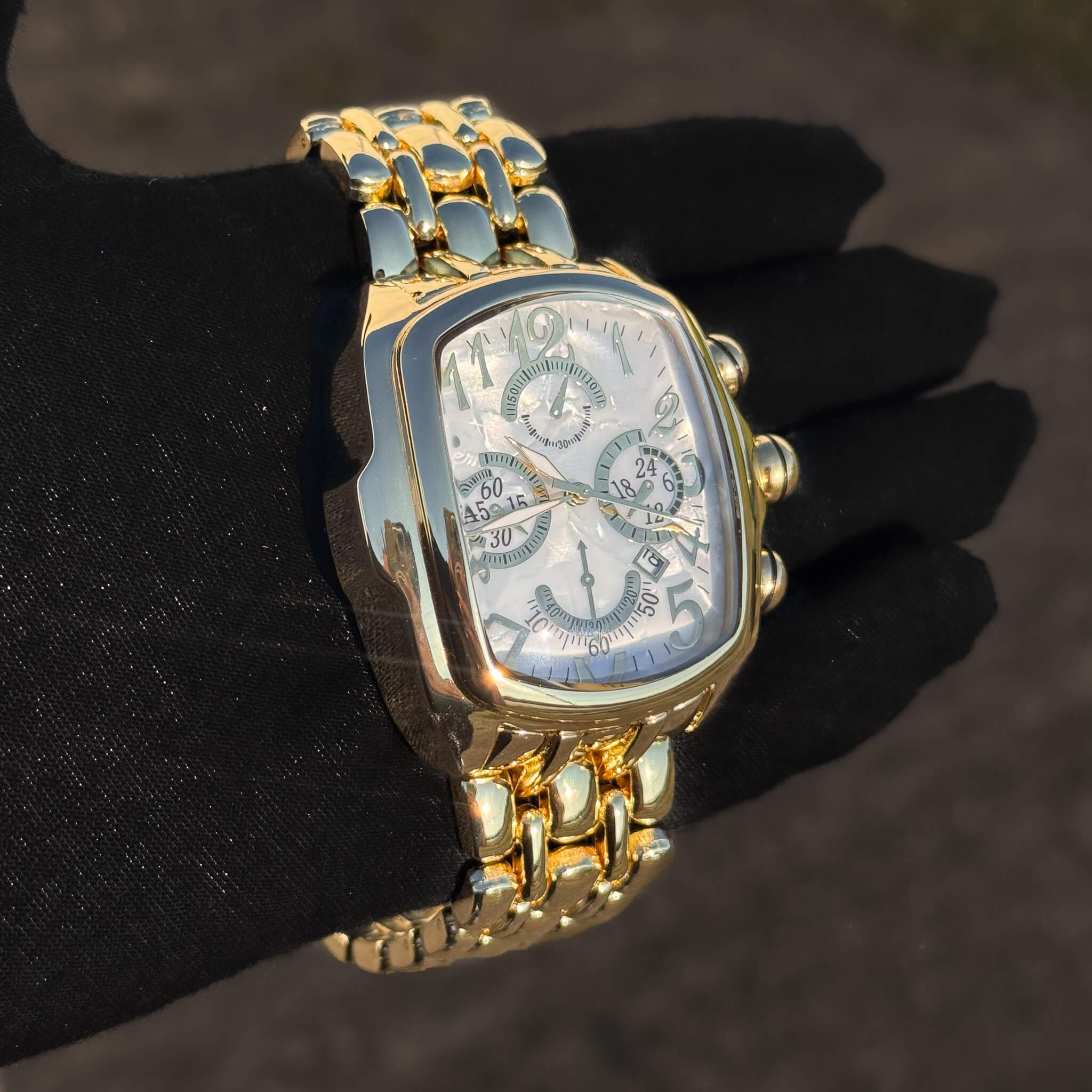Men’s 43mm gold tonneau watch with white chronograph dial and polished metal band design.