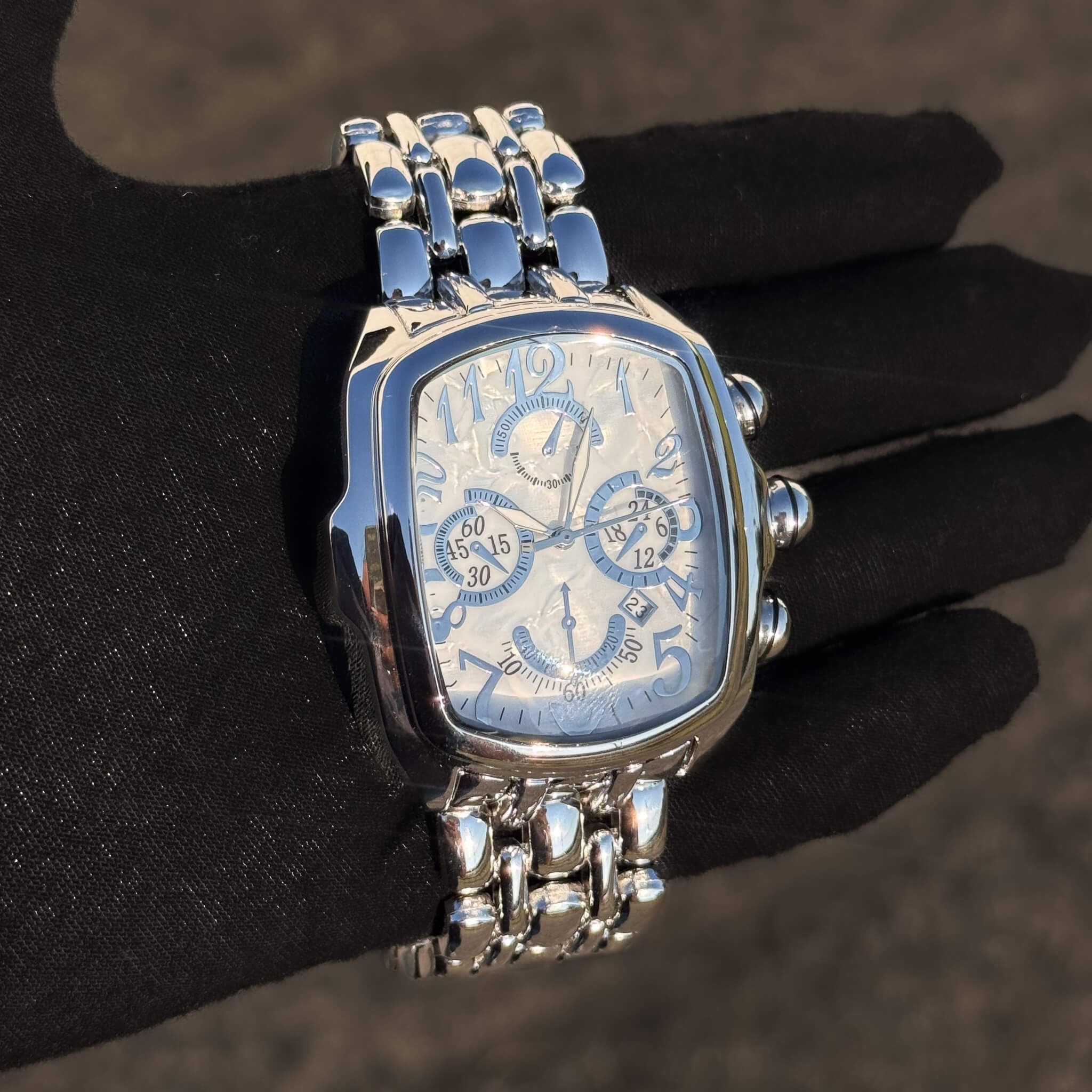 Men’s 43mm silver tonneau watch with white chronograph dial and polished linked metal band.