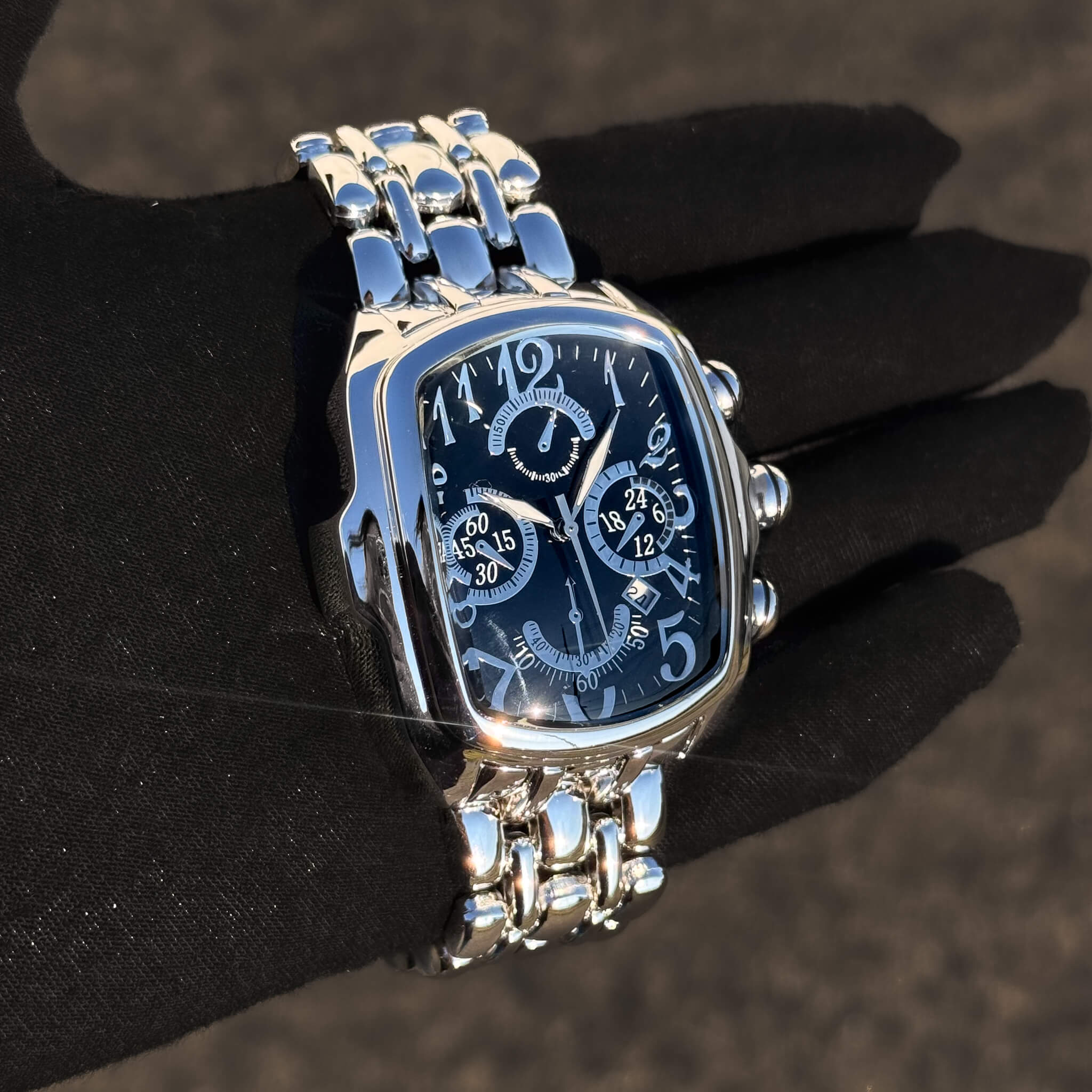 Men’s 43mm tonneau watch in silver with black multi-dial face and sleek metal band design.