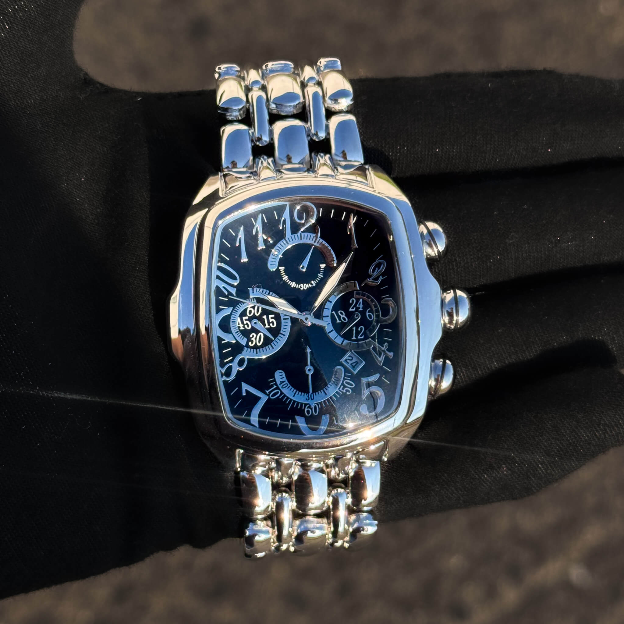 Men’s 43mm silver tonneau watch with black chronograph dial and polished stainless bracelet.