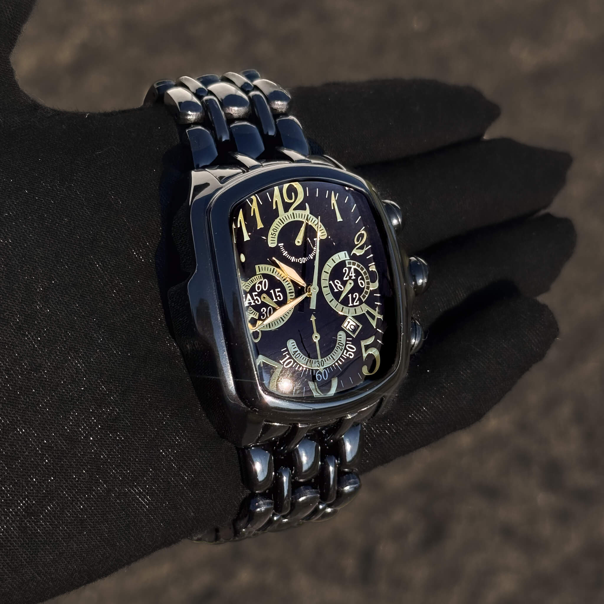 Men’s 43mm Tonneau Watch featuring steel bracelet, gold markers and black dial.