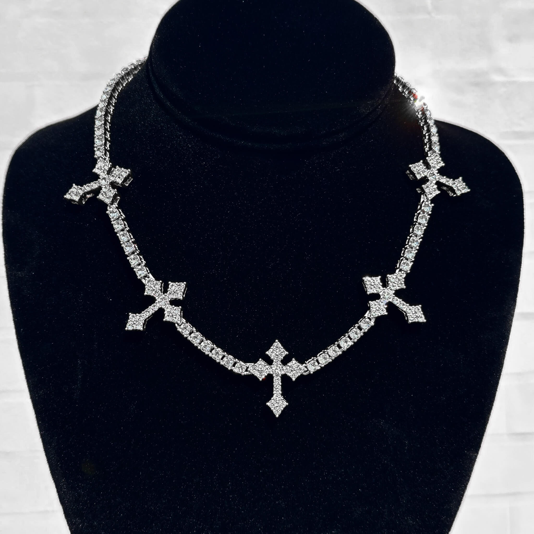 Silver Iced Crosses Tennis Choker with shimmering pavé cross charms shown on a black velvet display stand.
