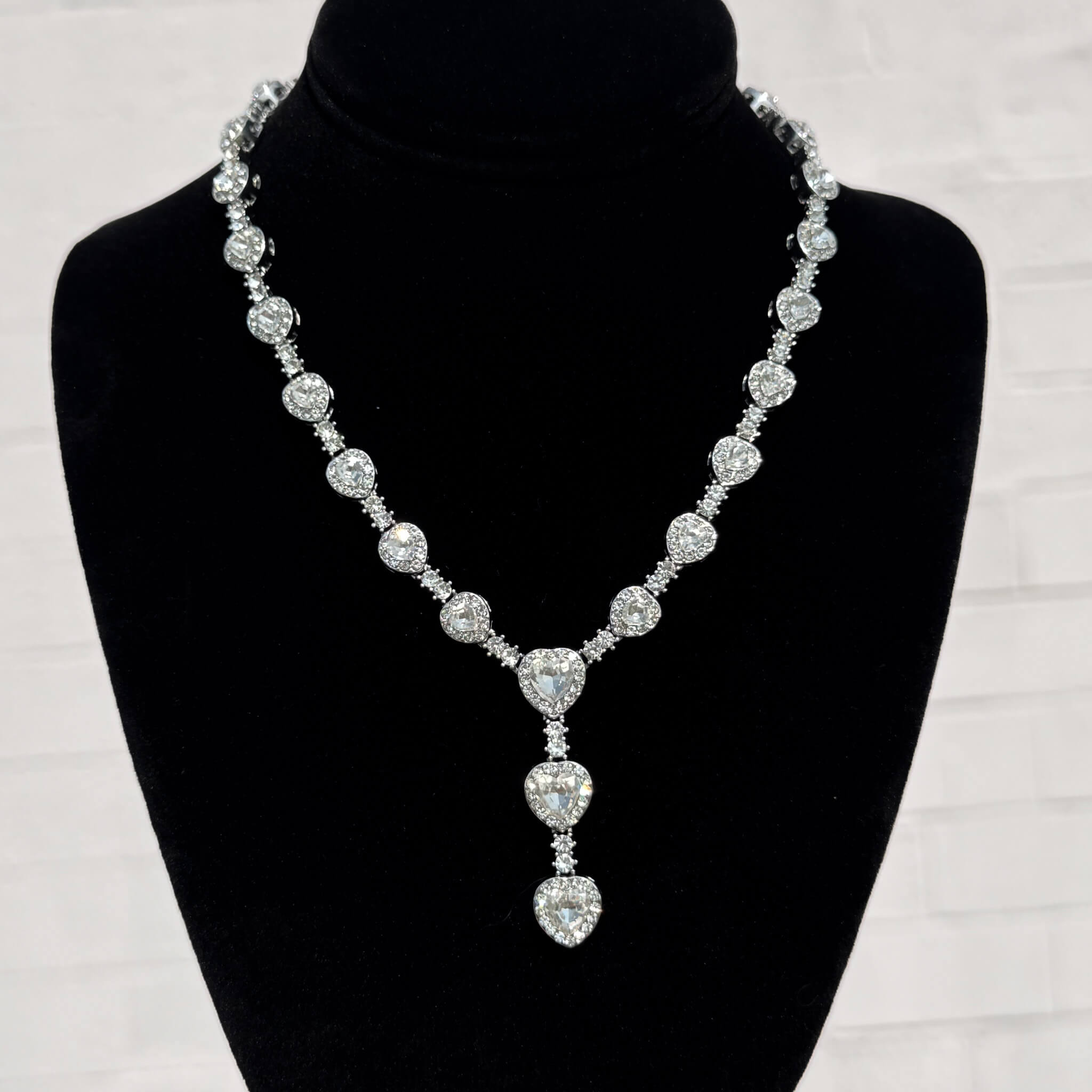 Silver Iced Heart Stone Lariat Necklace with shimmering heart-cut stones displayed on a black velvet stand.