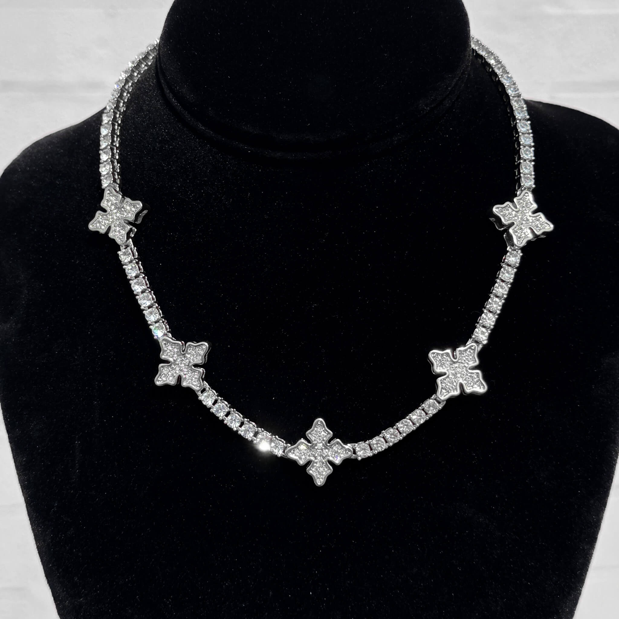 Silver Iced Mini Cross Tennis Choker with shimmering pavé cross accents shown on a black velvet display.