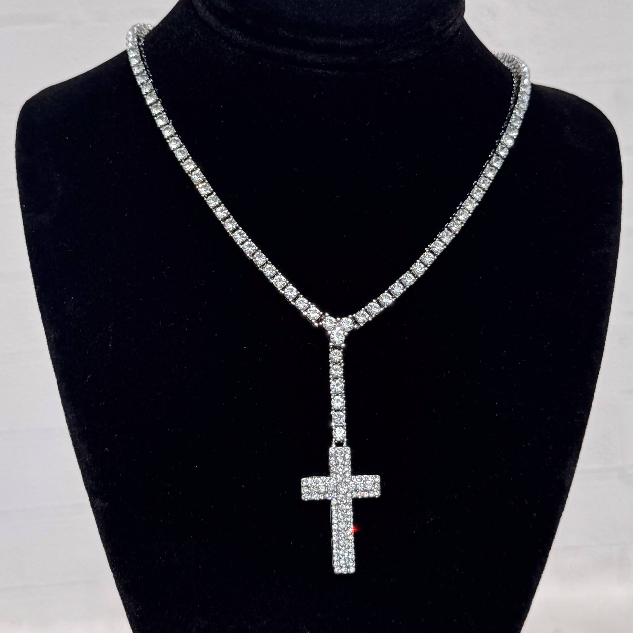 Silver Iced Cross Lariat Tennis Necklace with pavé crystal cross pendant shown on a black velvet stand.
