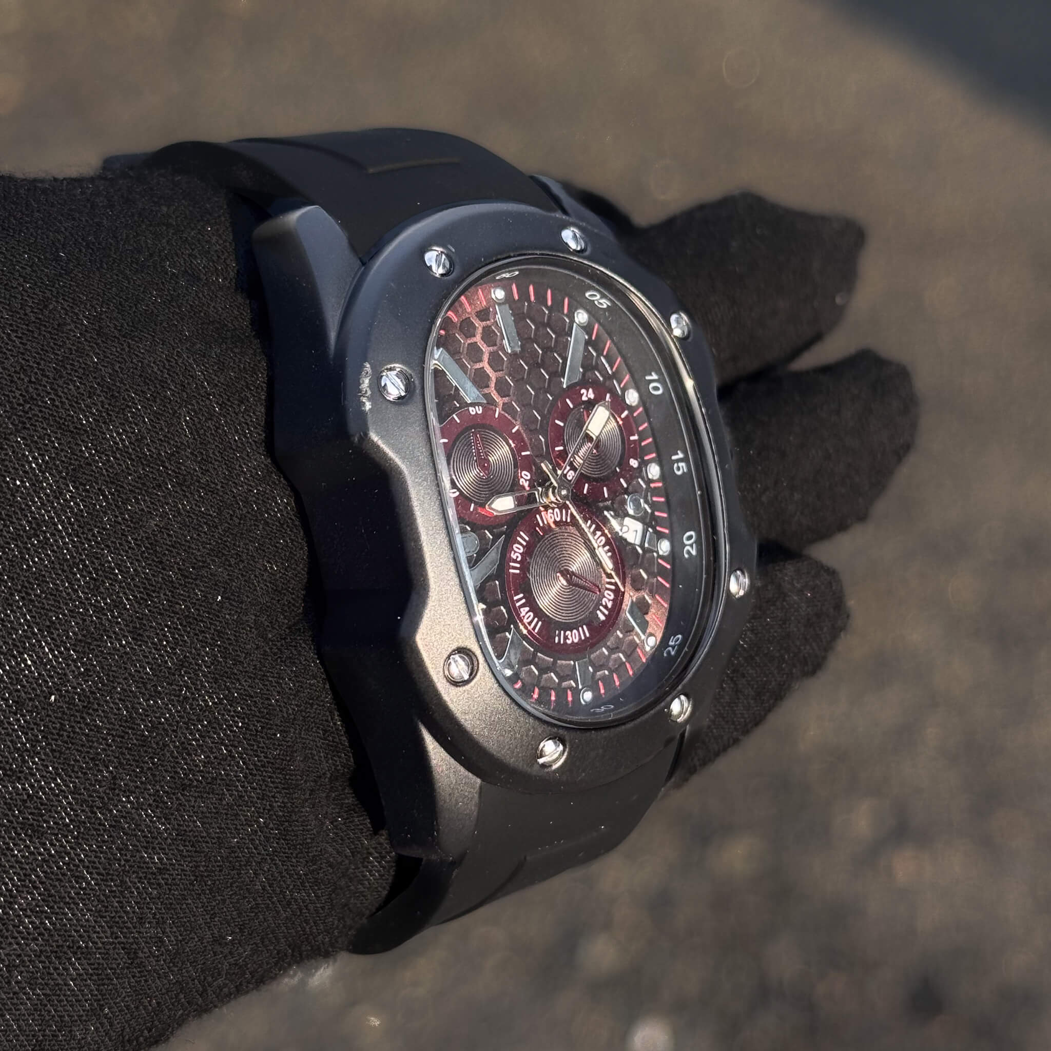 Angled Men’s 40mm Classic Black Watch showing red subdials and detailed honeycomb pattern.
