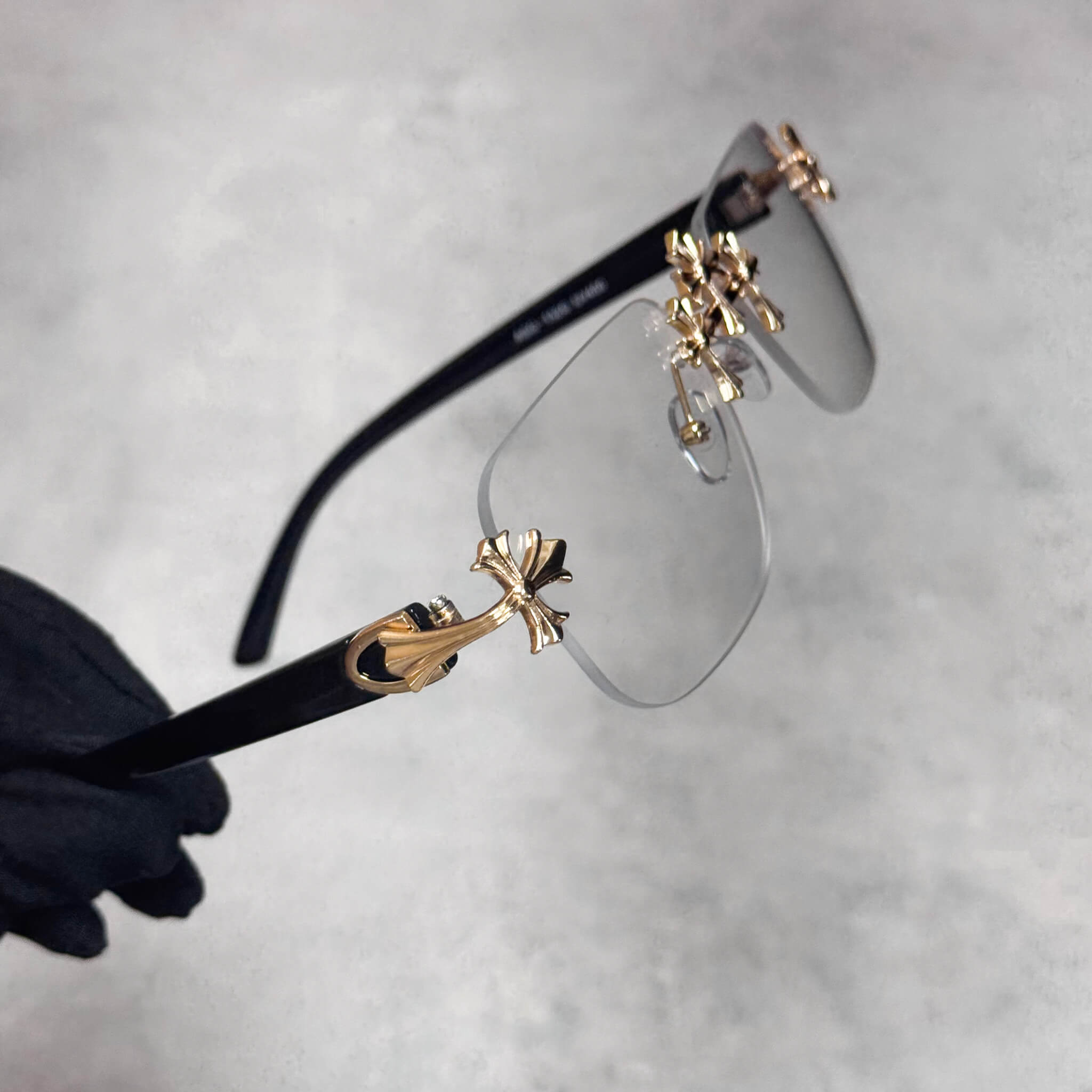 Clear-lens Solid Triple Cross Sunglasses featuring gold metal crosses and black arms.