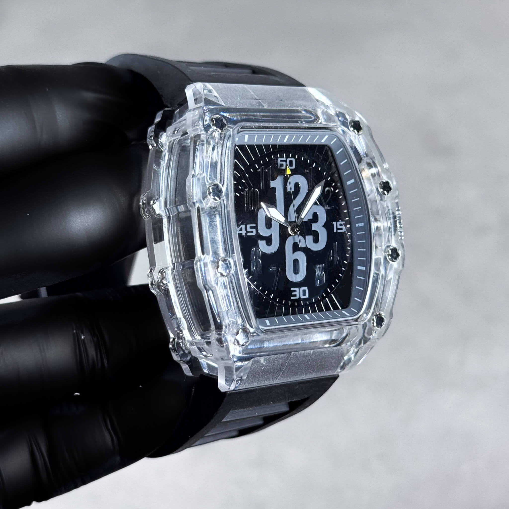 Side view of clear-case tonneau watch featuring black dial, bold numerals and black silicone band.