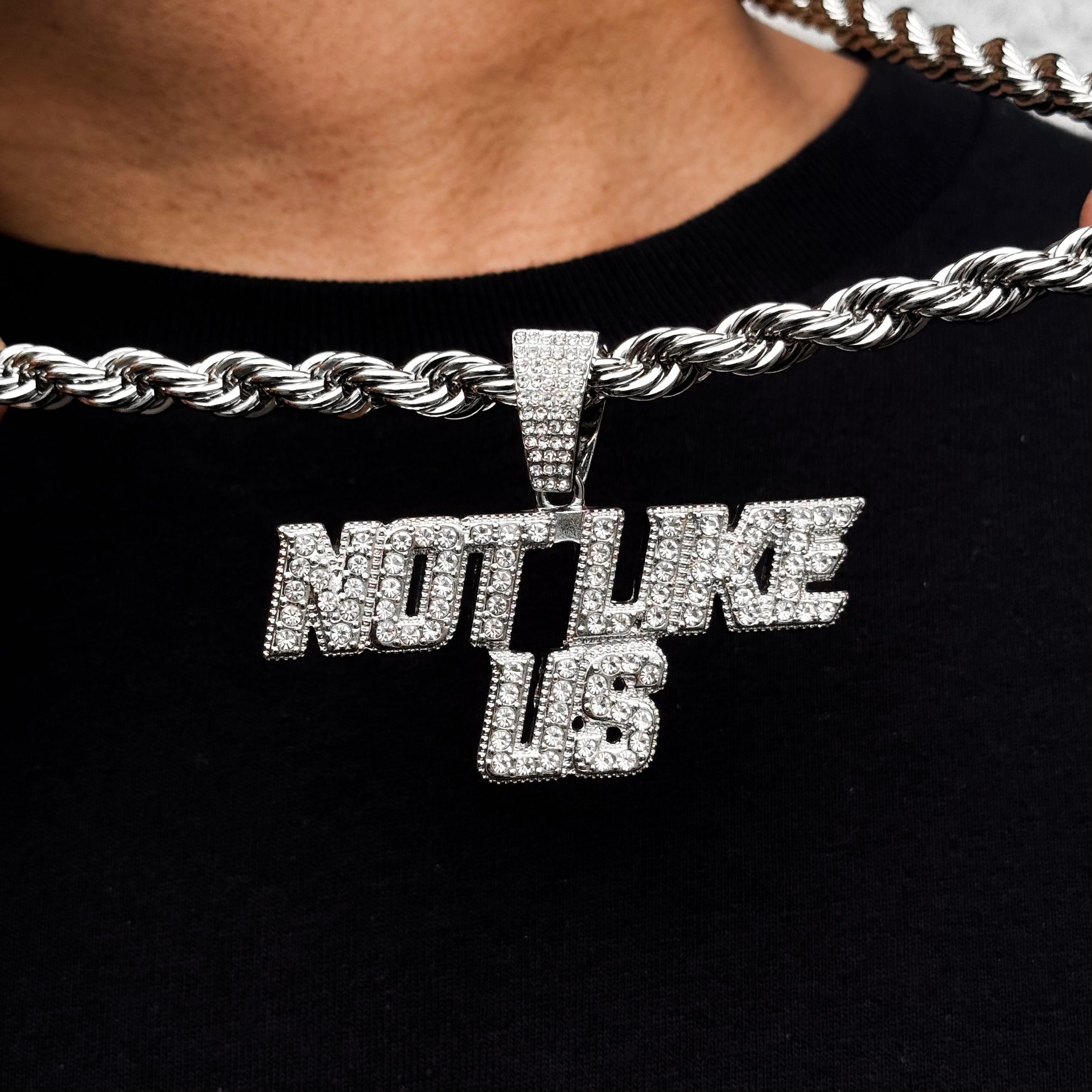 Silver iced-out Not Like Us pendant on men’s 8mm rope chain, bold hip-hop statement piece