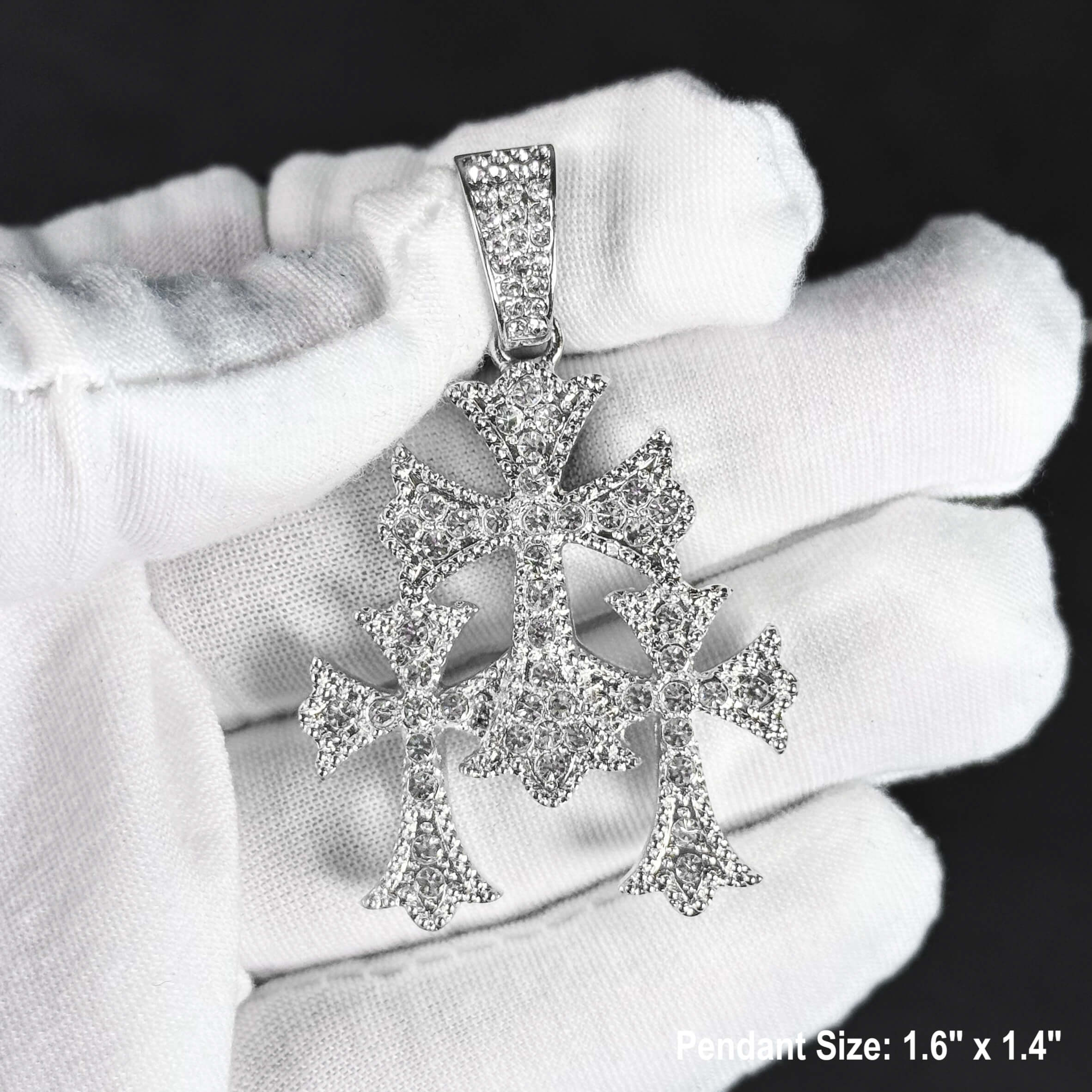Silver iced out triple cross pendant for men, fully covered in clear stones, shown in hand.