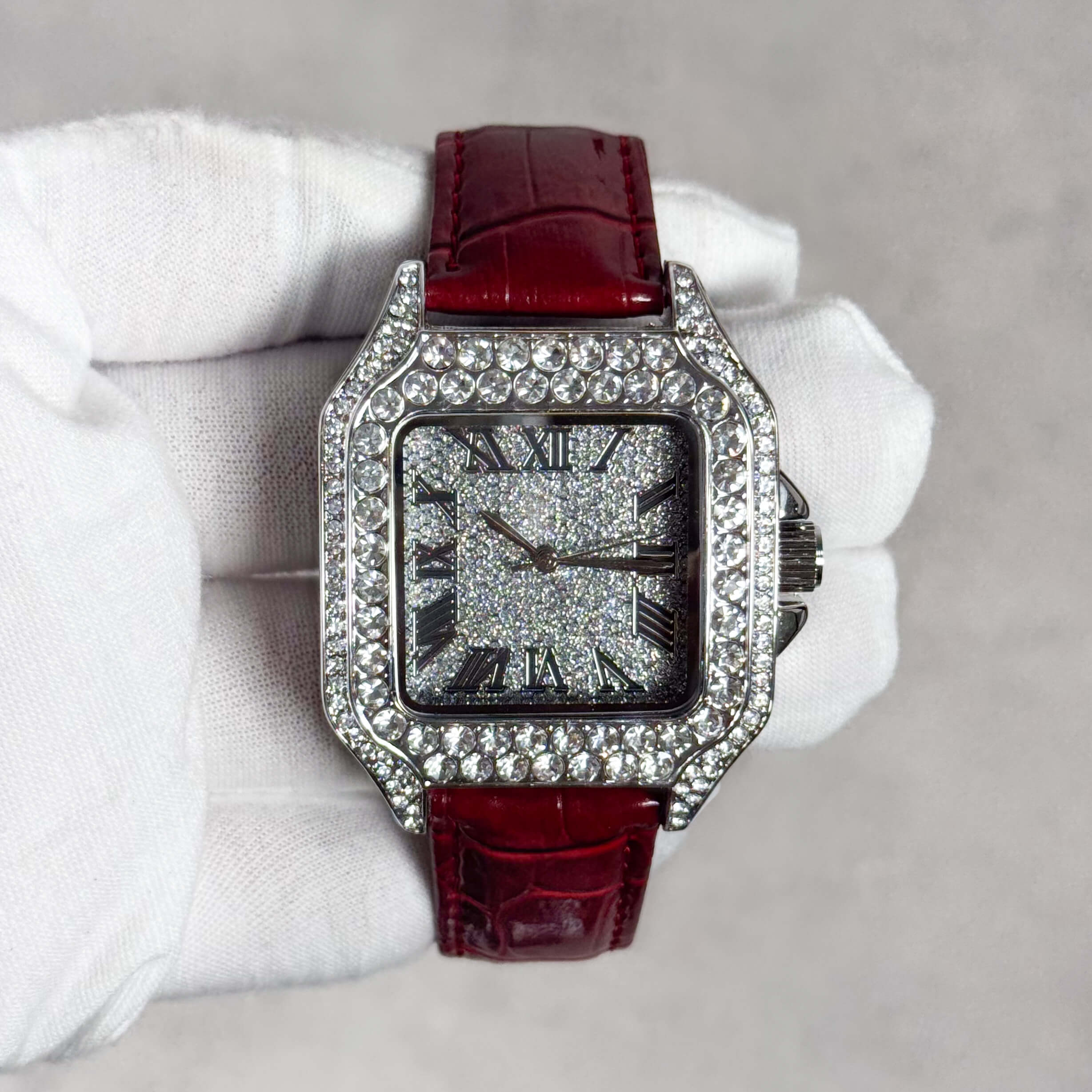 Men's 32mm square dial iced out watch with silver crystal case and red leather band.