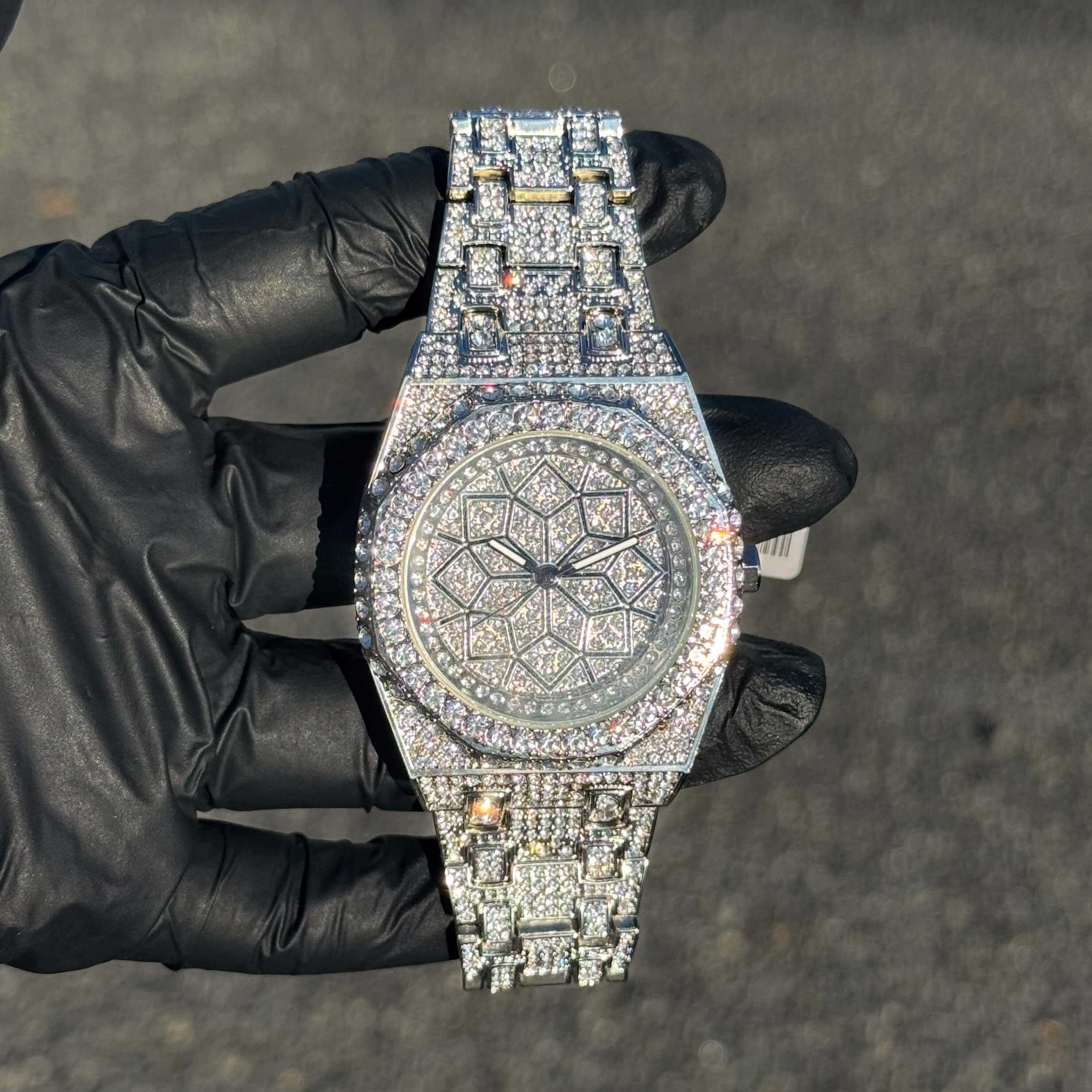 Men's 43mm silver iced out octagon shape watch with diamond-style stones and patterned dial.