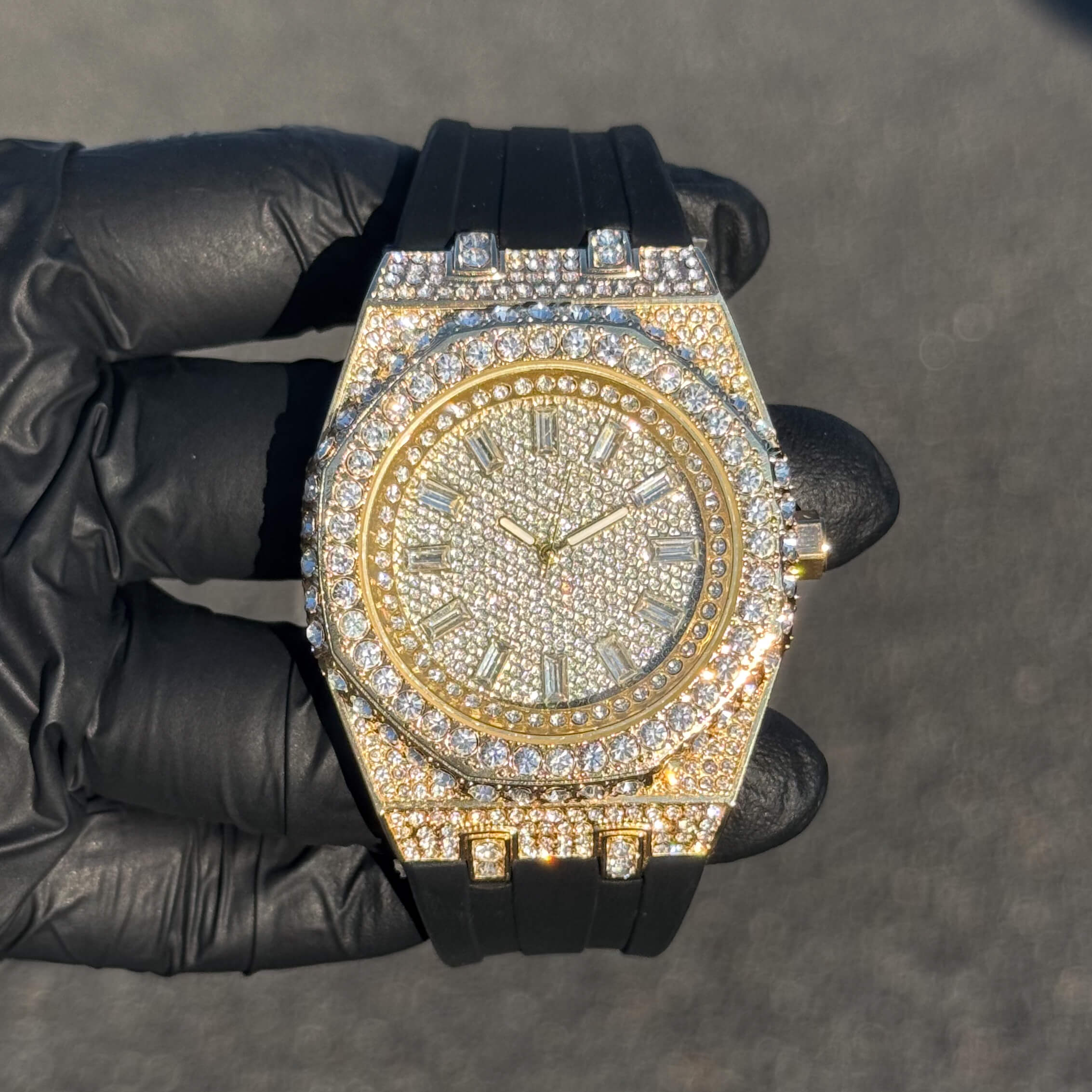 Men's 43mm gold iced out octagonal dial watch with diamond bezel and black silicone band.