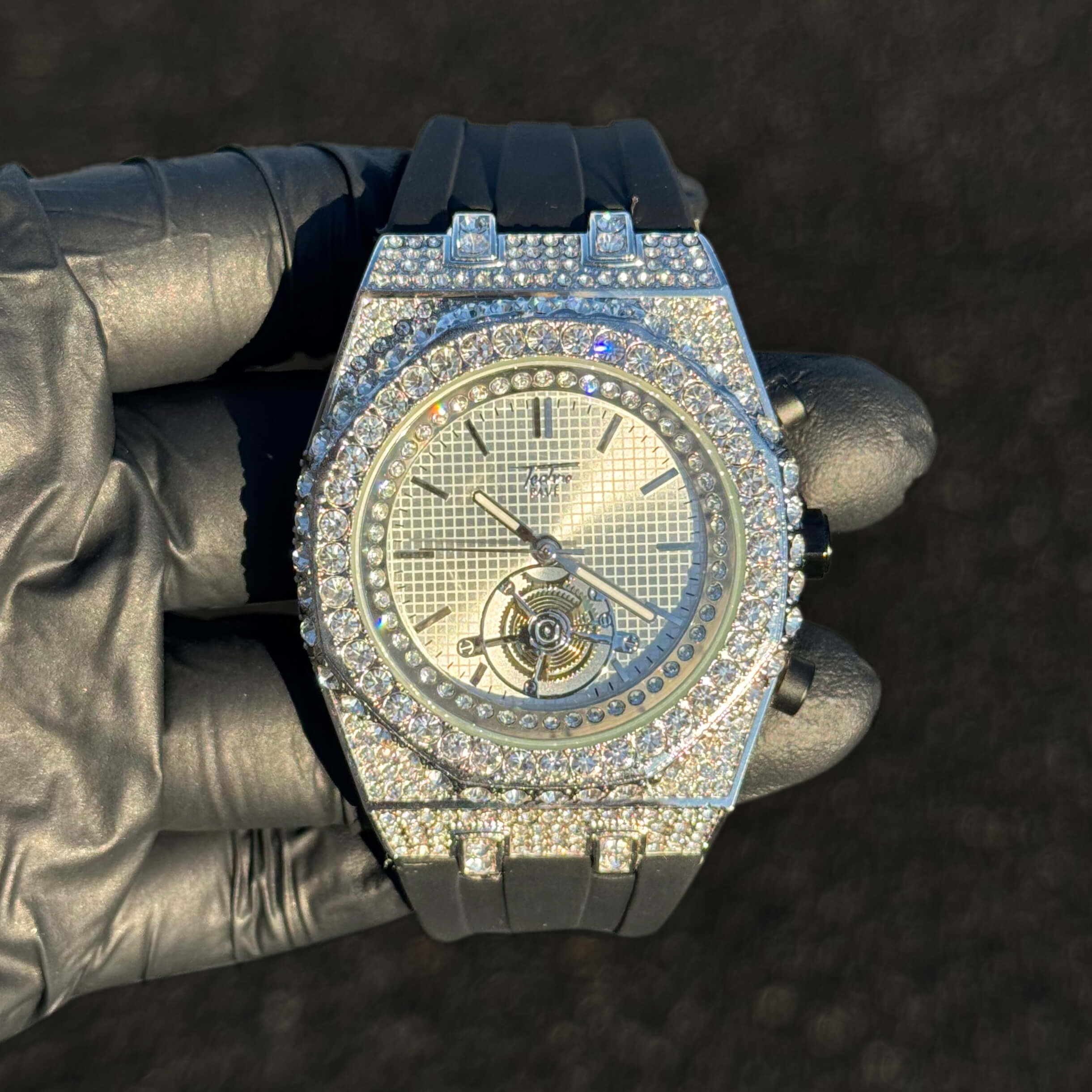 Men's 43mm silver iced out octagonal case watch with crystal bezel and black silicone band.