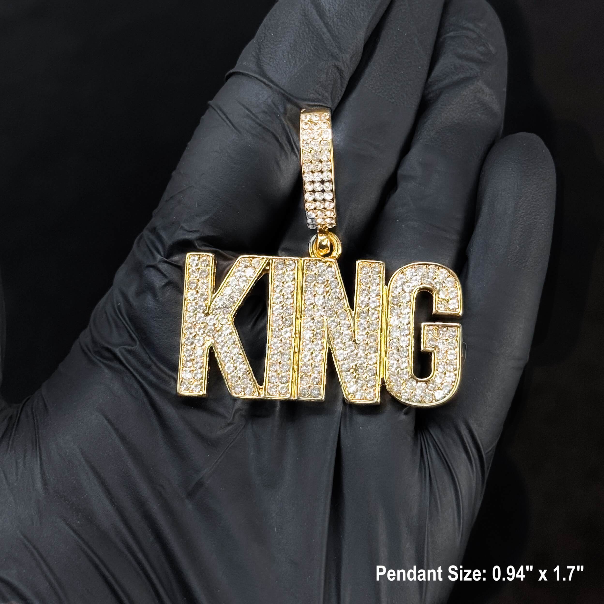 Close-up gold iced-out KING pendant for men, sparkling pavé letter design displayed in gloved hand.