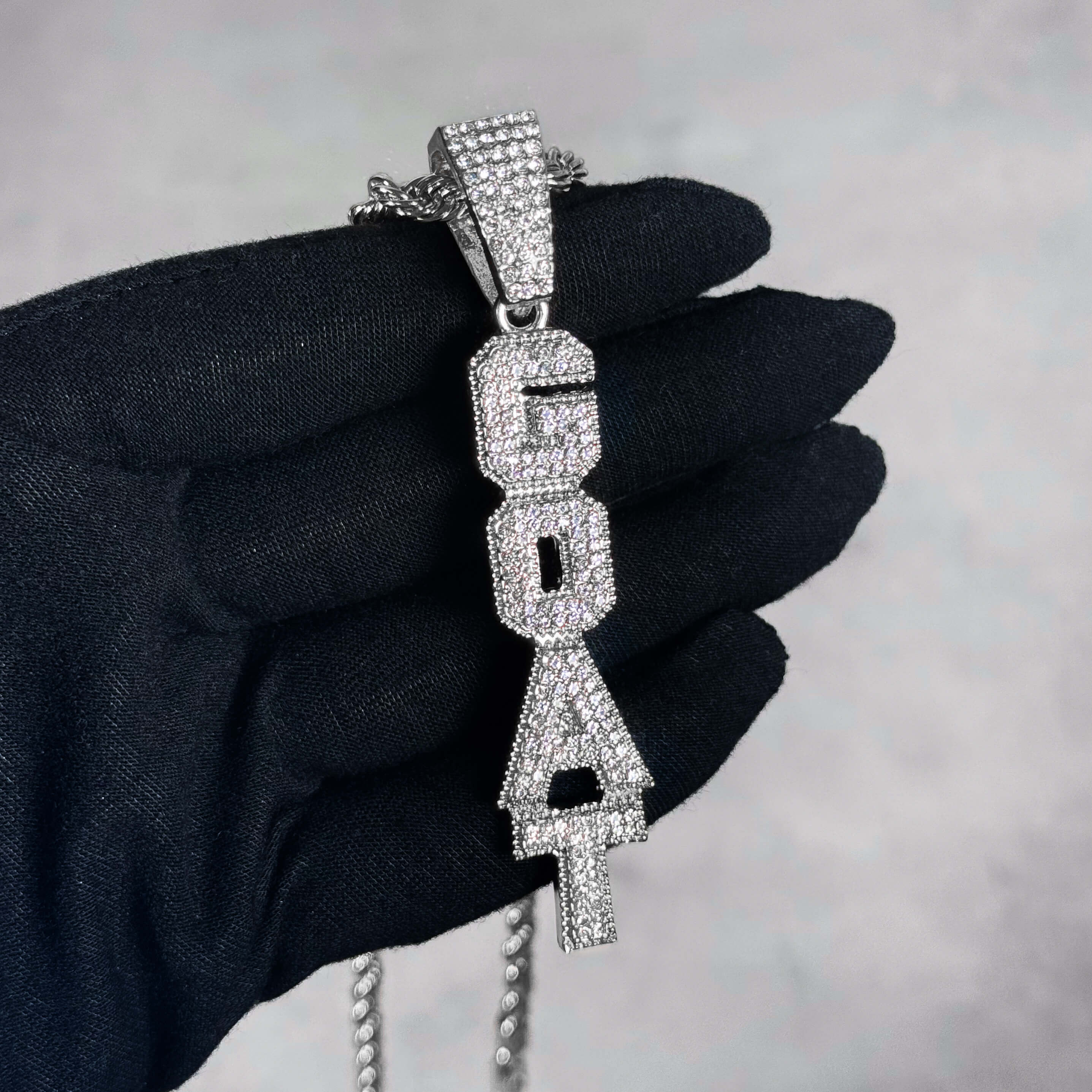 Silver Iced out Vertical Goat Pendant held in hand, pavé CZ vertical letter necklace.