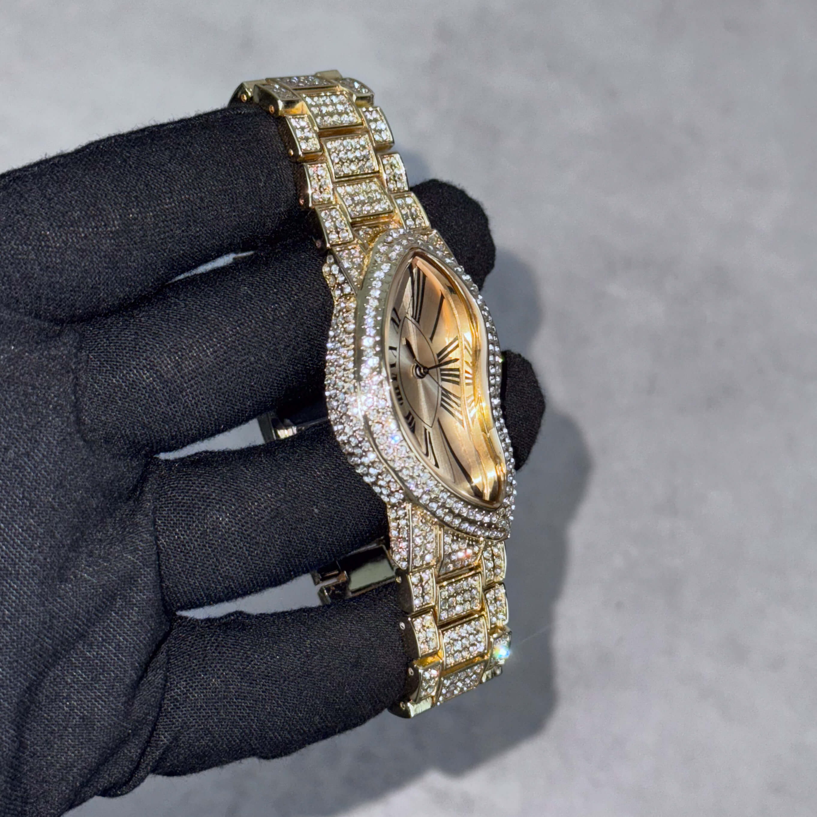 Men’s 30mm gold warped watch shown from angle, highlighting iced-out bezel and crystal-covered bracelet.