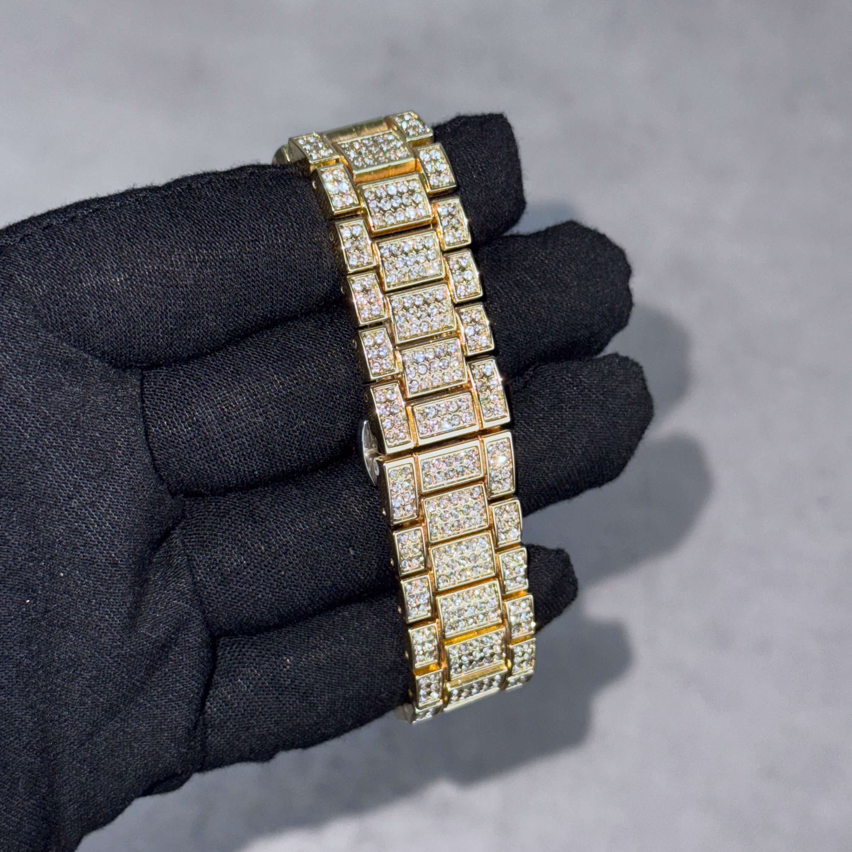 Luxury gold iced-out watch band with dense crystal link detailing for men’s warped dial timepiece.