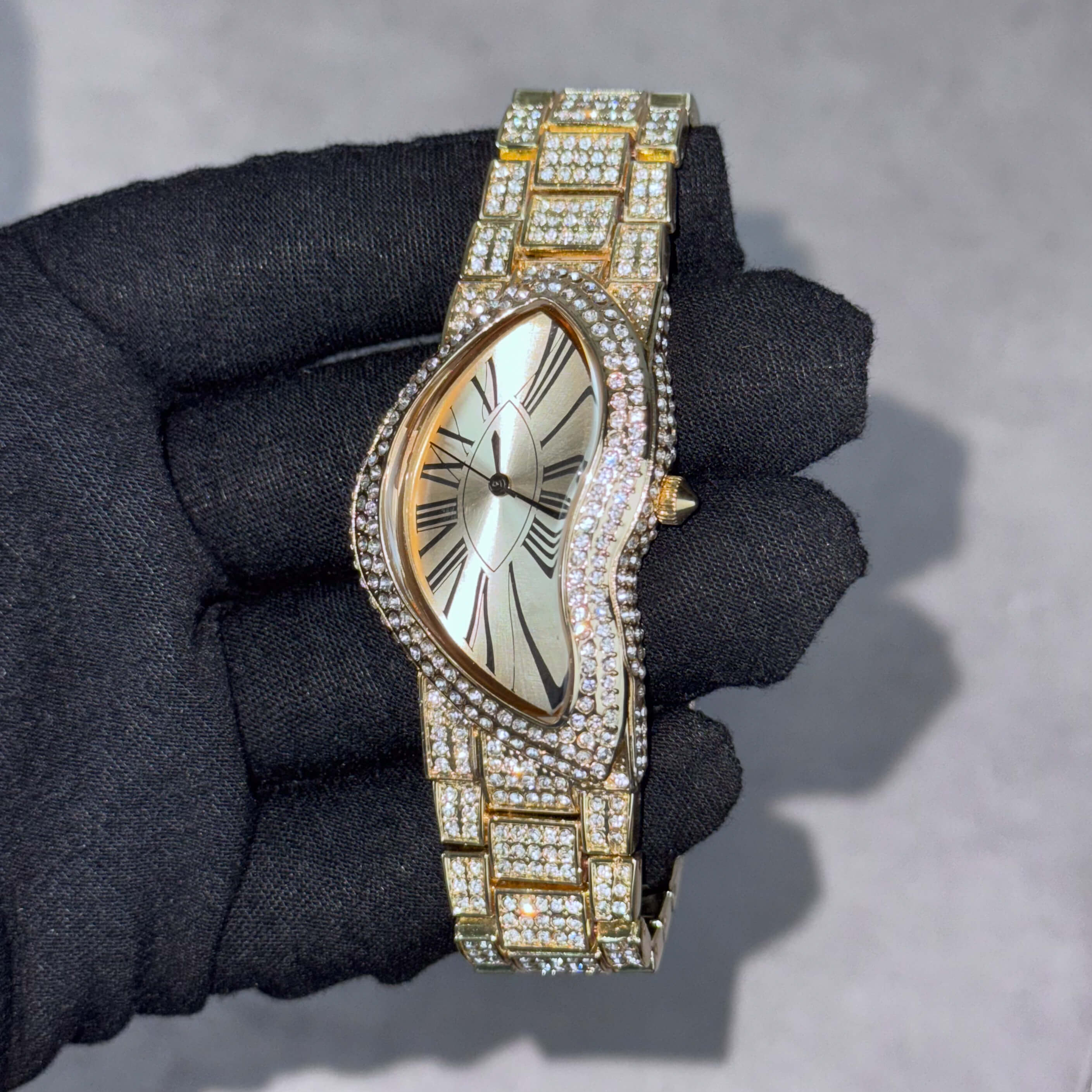 Men’s 30mm gold warped dial watch with Roman numerals and full crystal setting on bezel and bracelet.