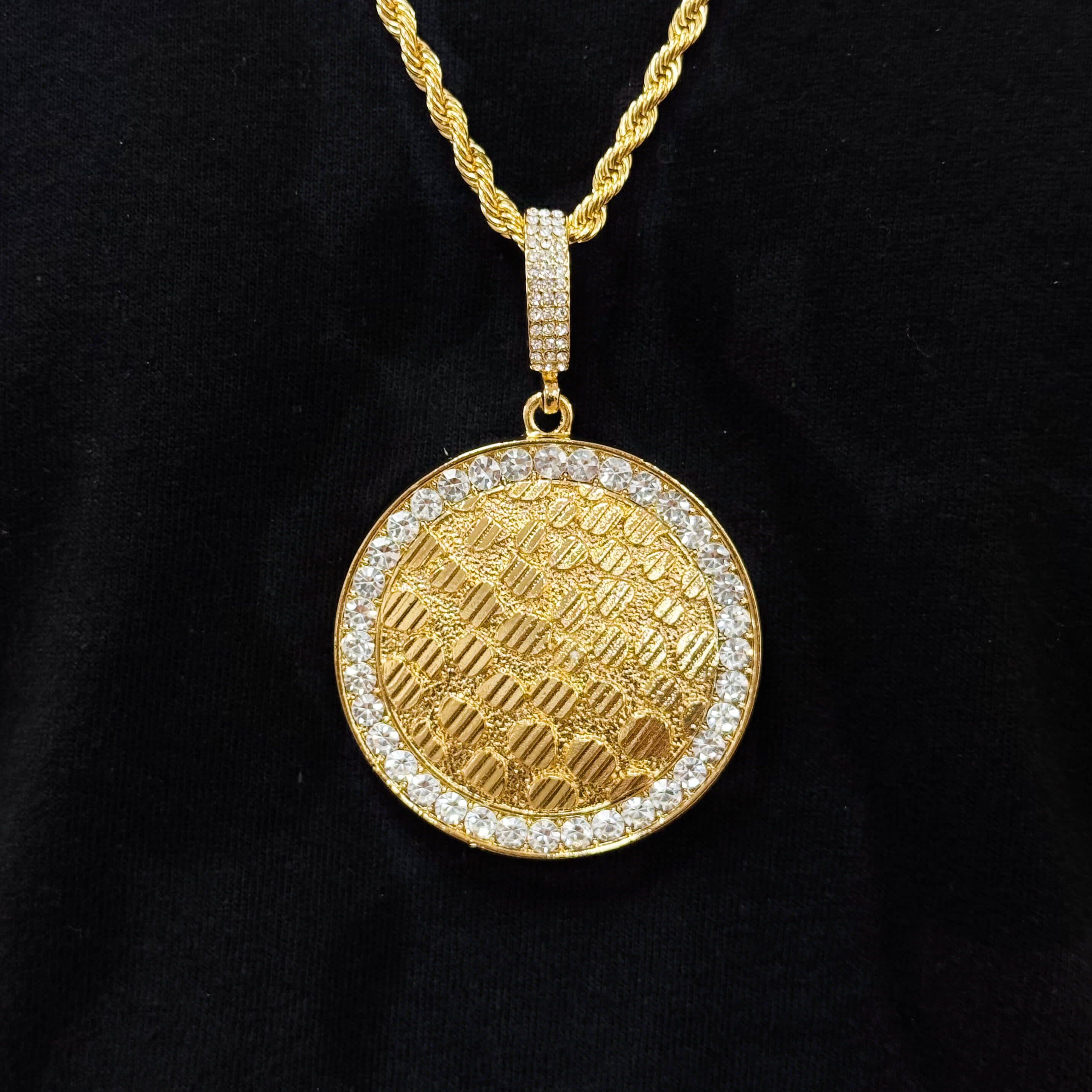 Men's gold medallion pendant featuring crystal border and textured pattern on rope chain.