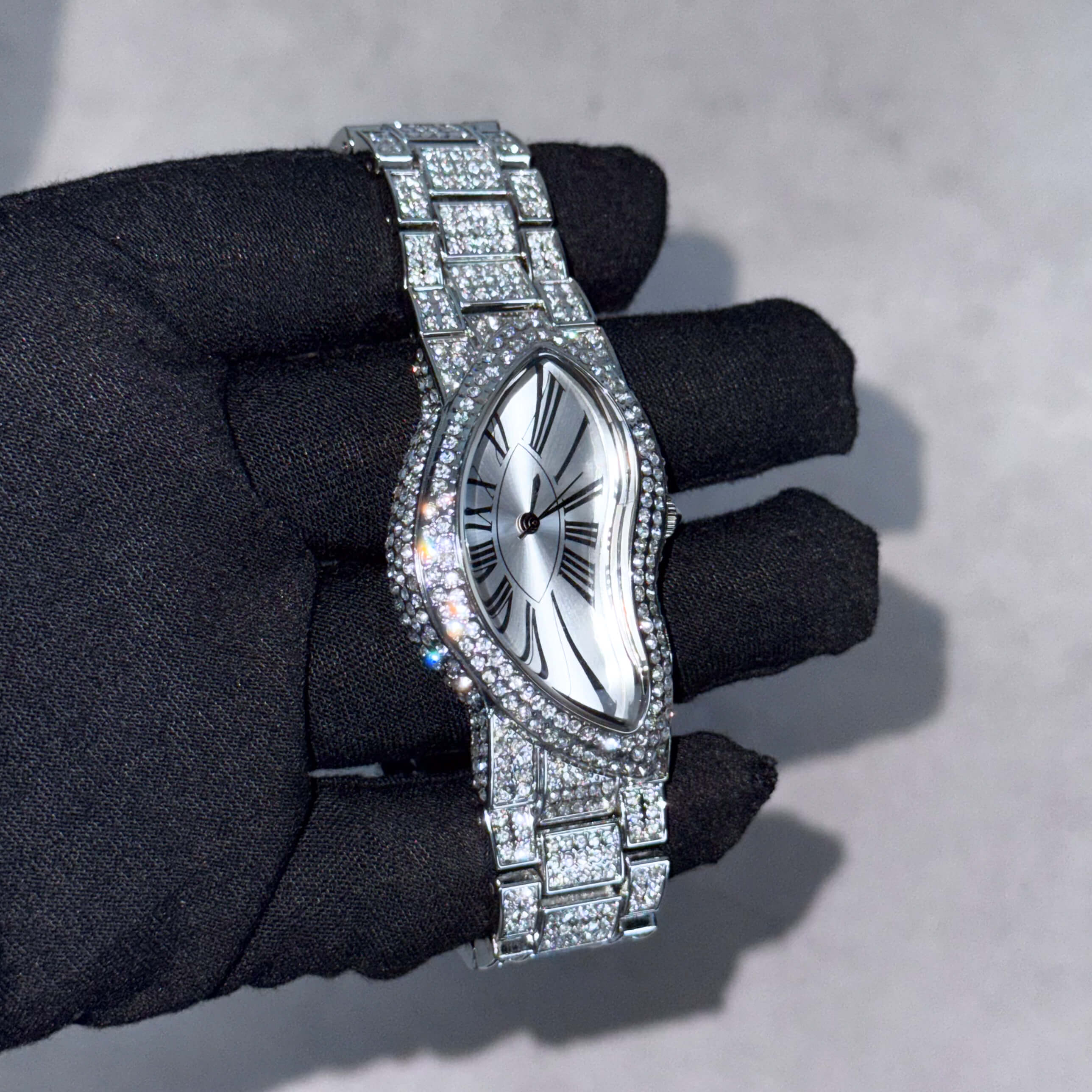 Men’s 30mm silver warped dial watch with iced-out bezel and crystal bracelet featuring Roman markers.