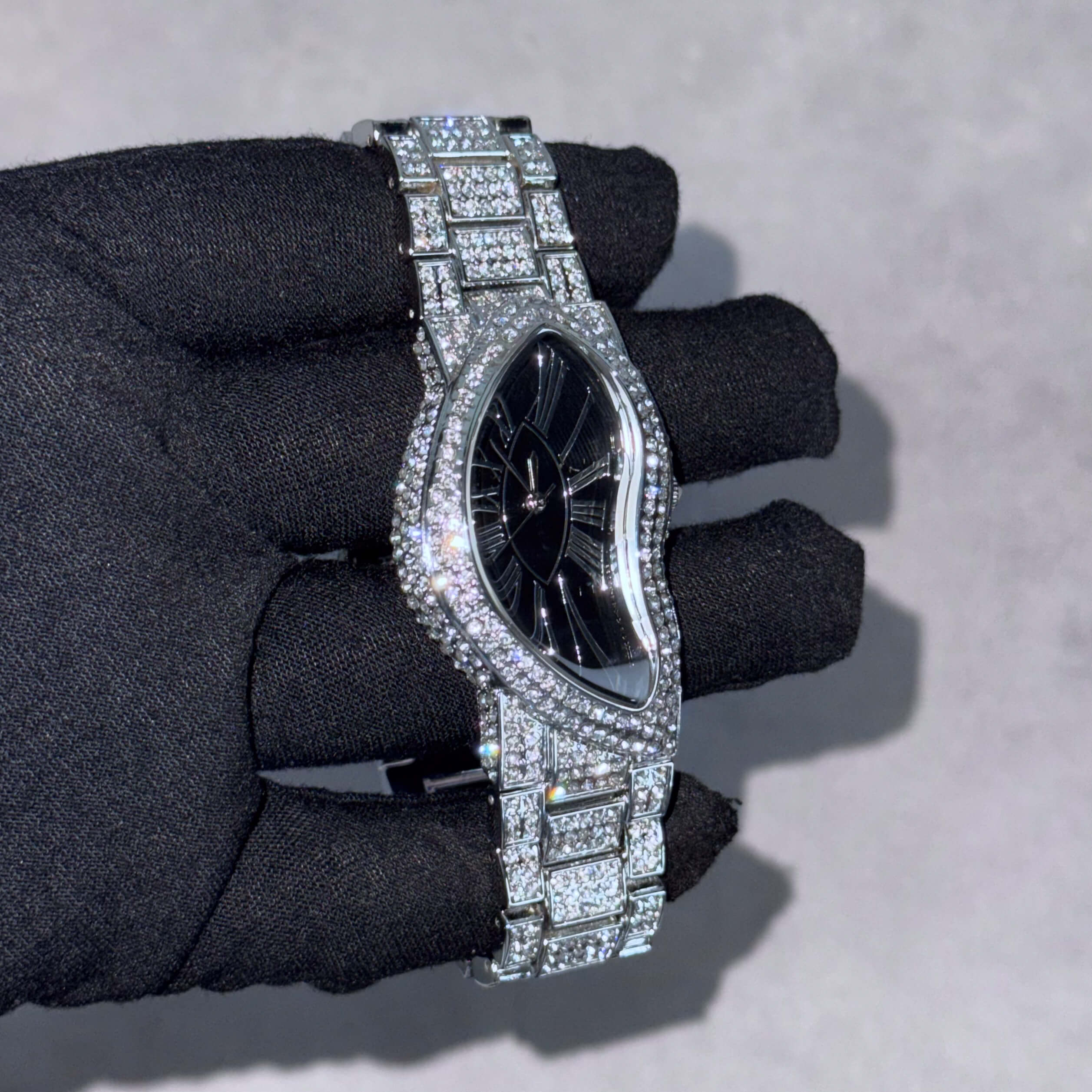 Silver Men's 30mm iced-out warped watch featuring a curved case, black dial and pavé bracelet.