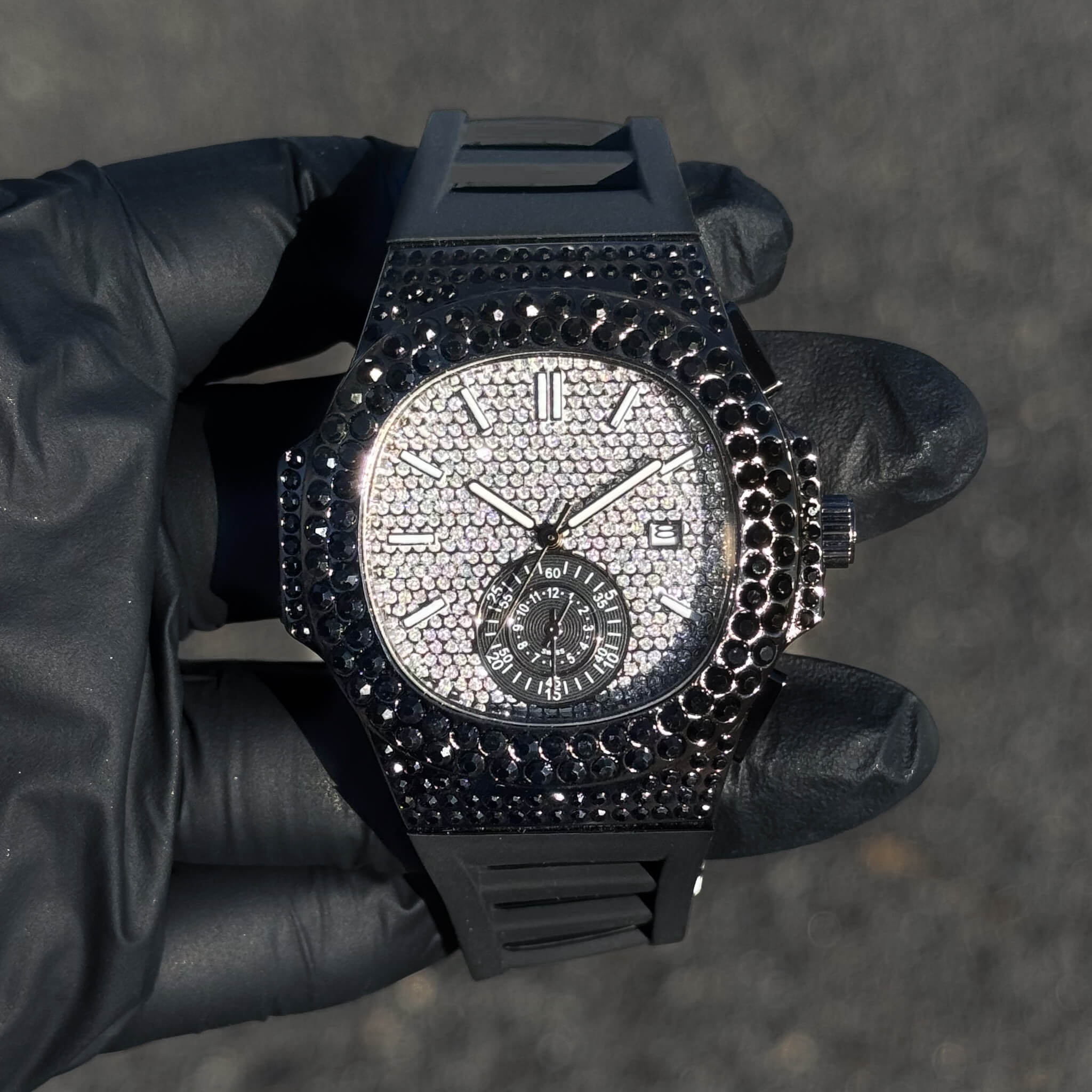 Men's 43mm black iced out silicone band watch with oblong bezel and diamond-paved dial accents.