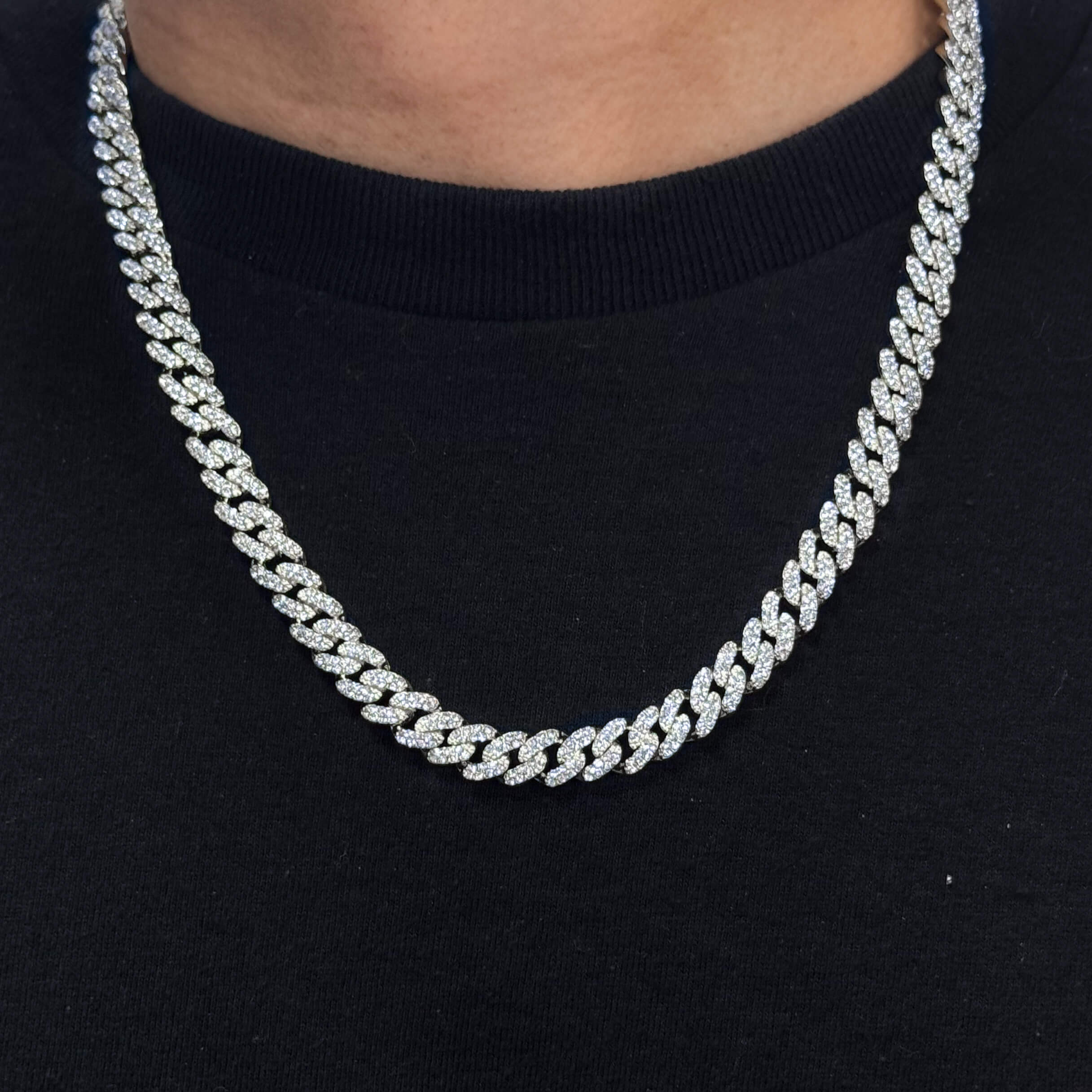 9mm Iced Out Cuban Chain in silver, pavé CZ diamond links, worn around neck close-up on black shirt.