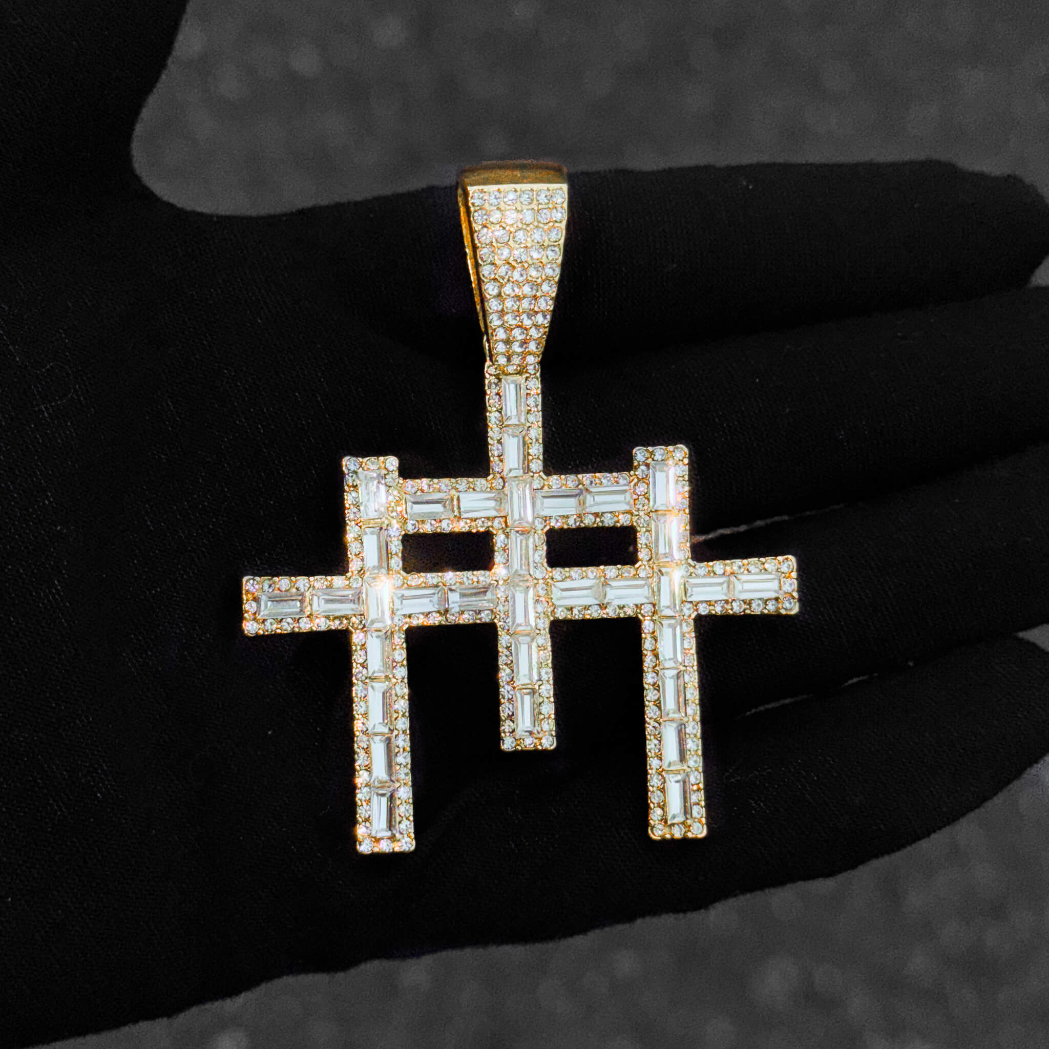 Close-up of men’s gold 55mm baguette iced-out cross pendant with shimmering stones.