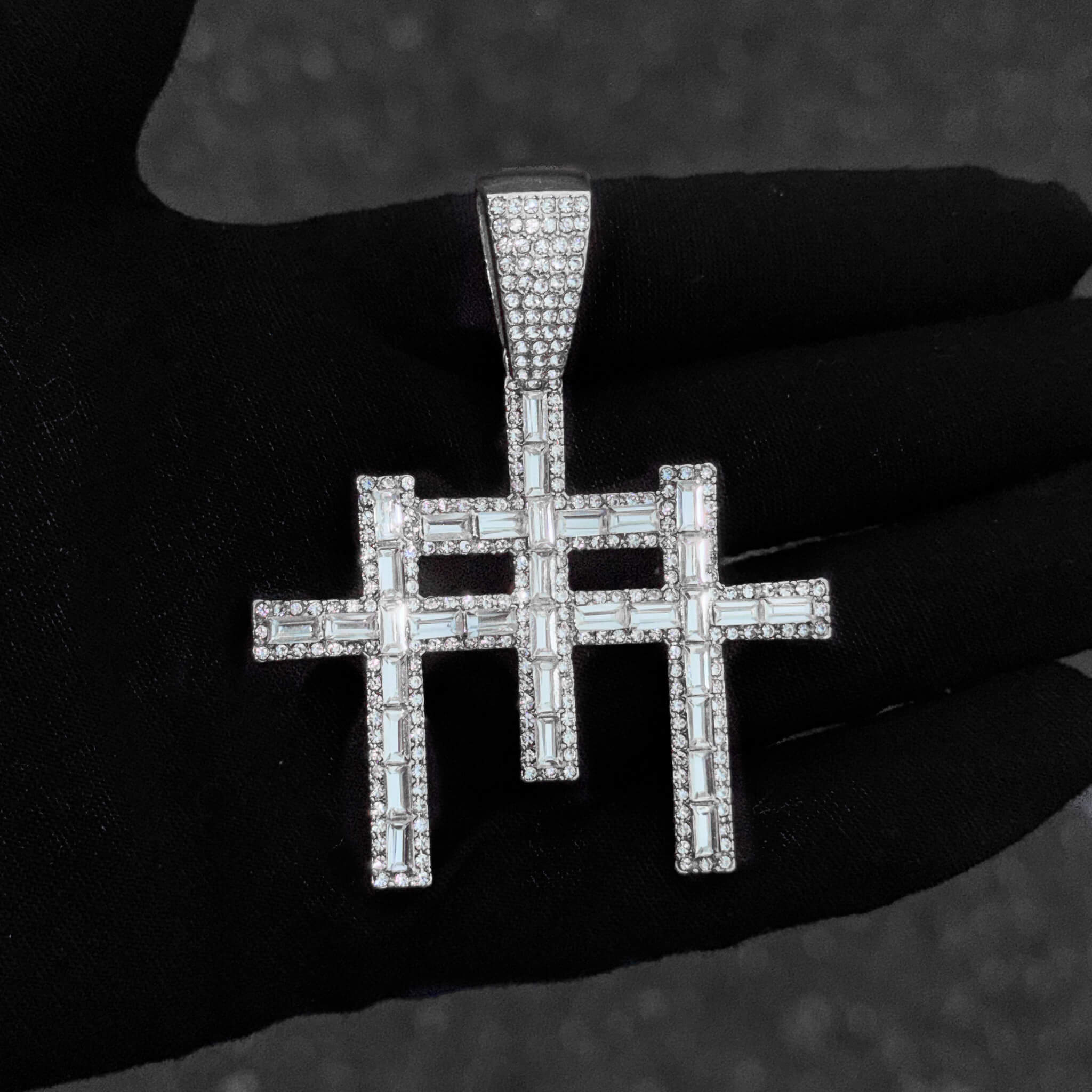 Detailed close-up of silver 55mm baguette iced-out cross pendant with sparkling stones.