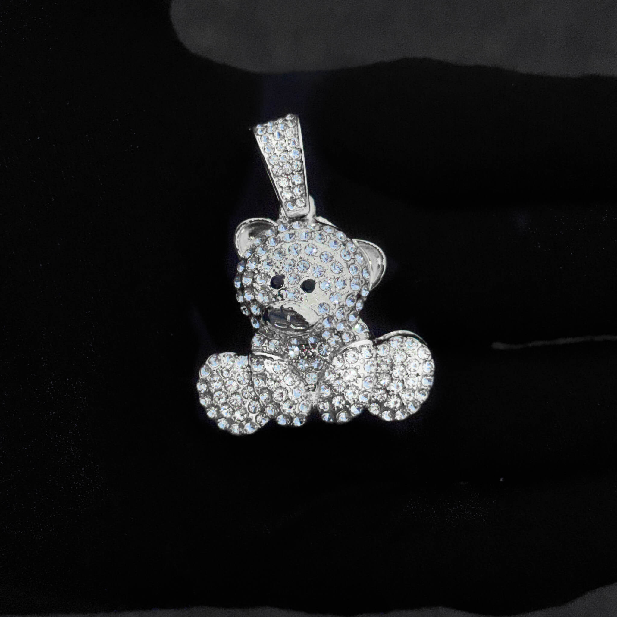 Detailed close-up of silver iced-out bear pendant covered in sparkling stones for women’s jewelry.