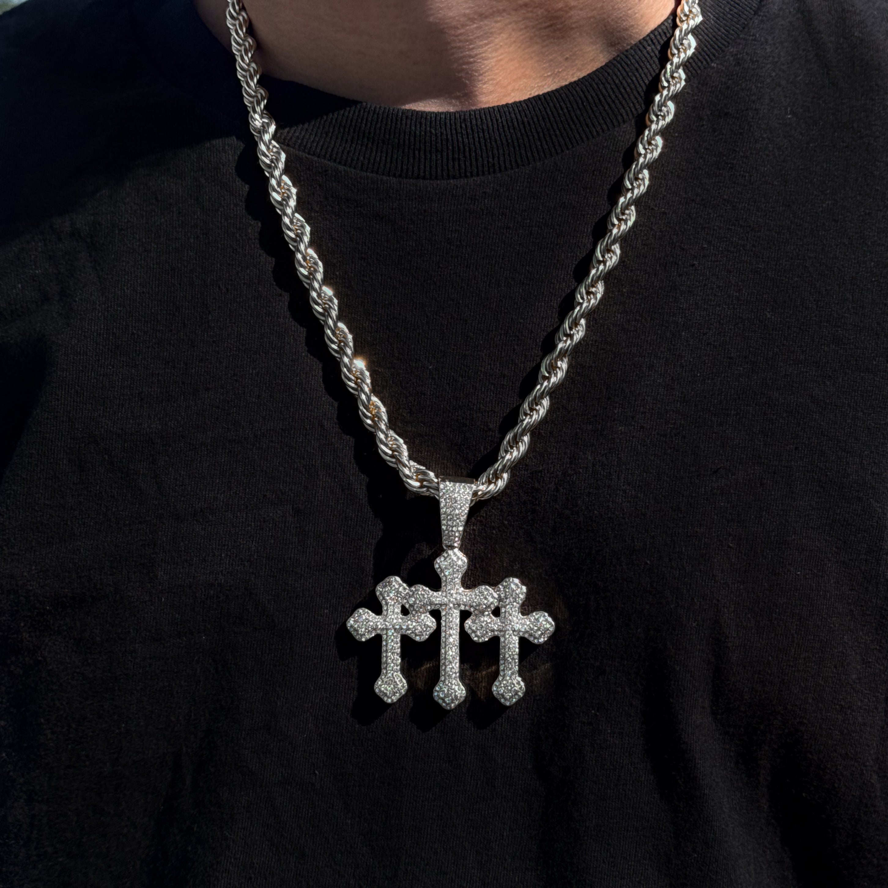 Men’s 60mm silver iced-out triple cross pendant with 8mm rope chain styled on black T-shirt.