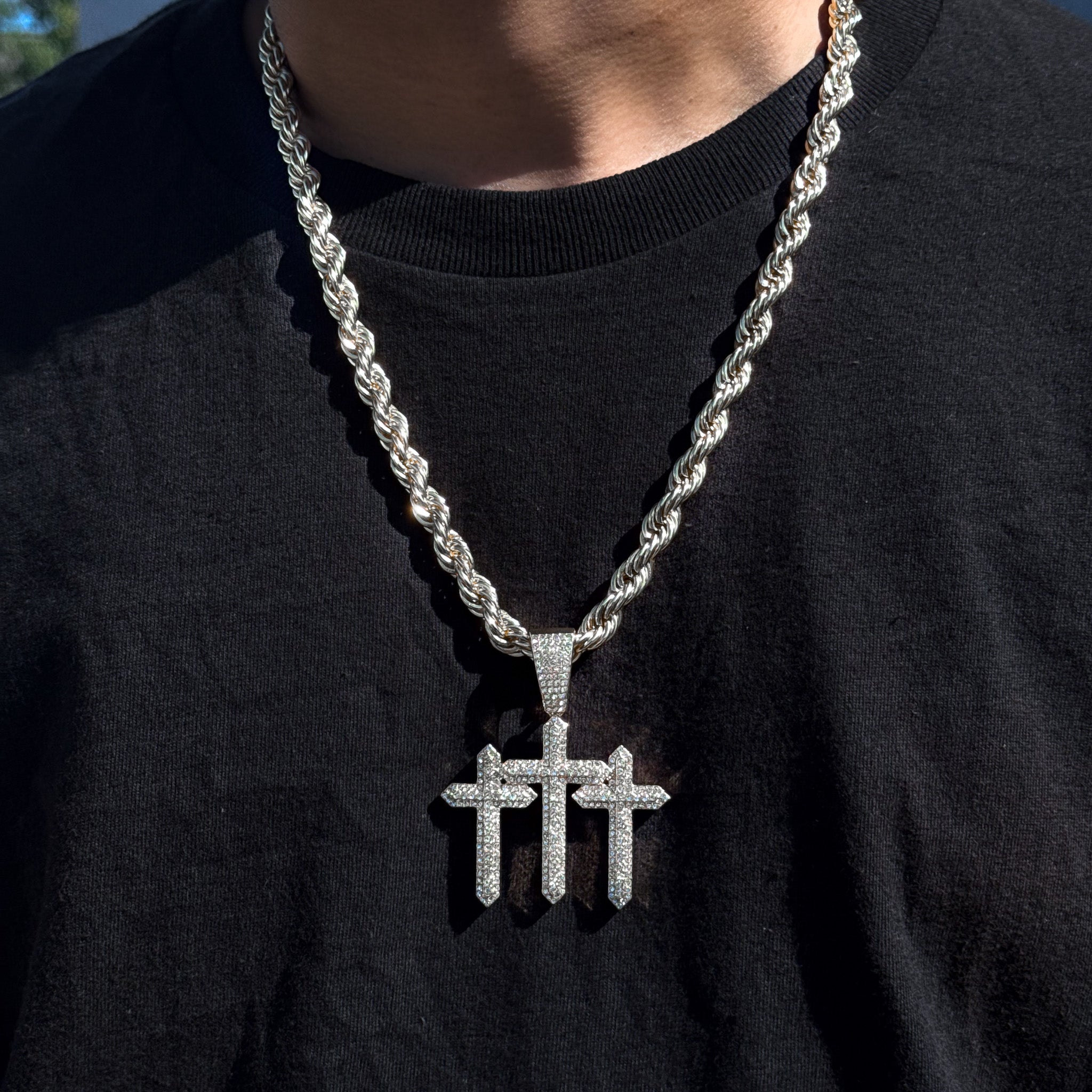 Men’s 53mm silver iced-out triple cross pendant with 8mm rope chain styled on black T-shirt.