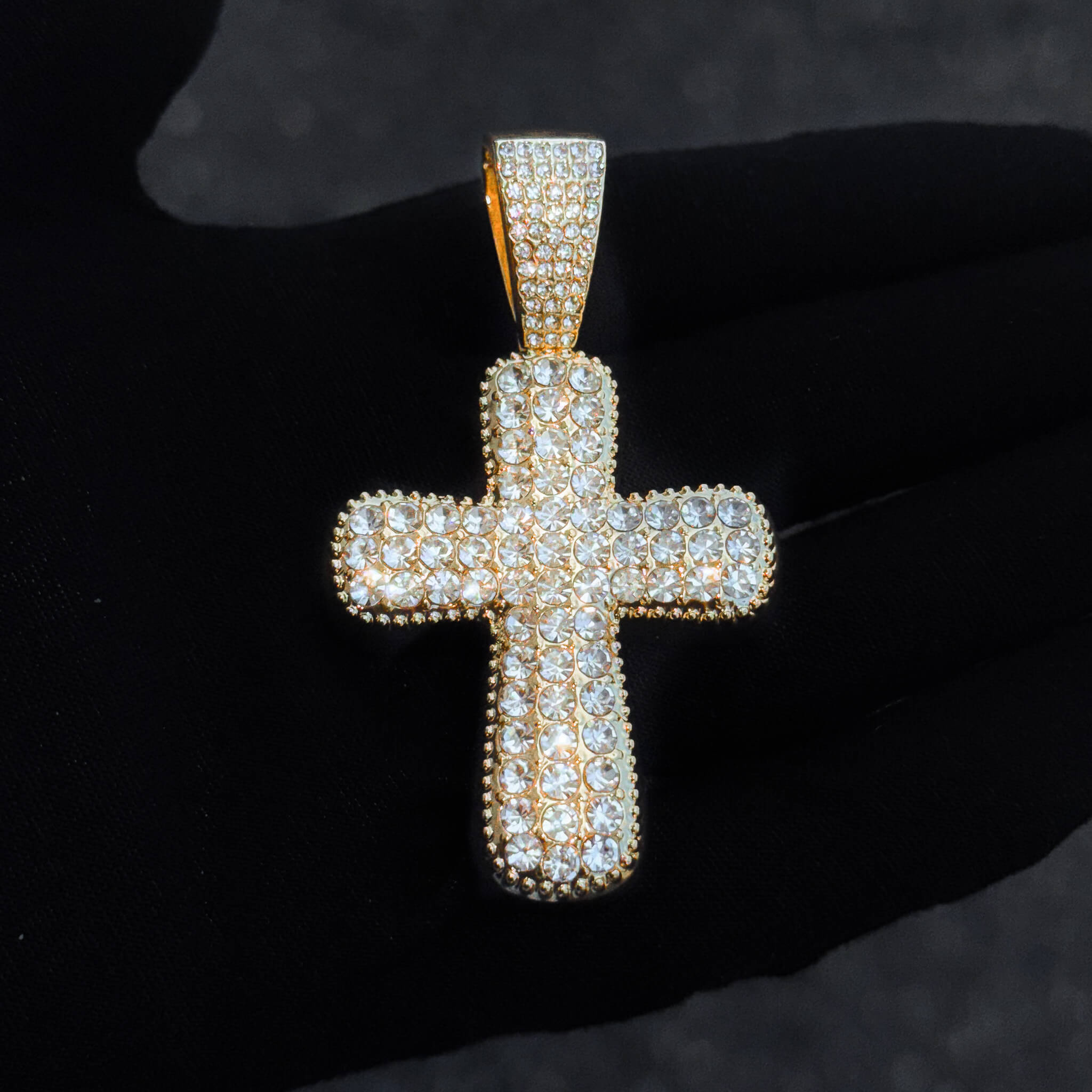 Close-up of gold iced-out 40mm cross pendant covered in round-cut crystals for women’s fashion jewelry.