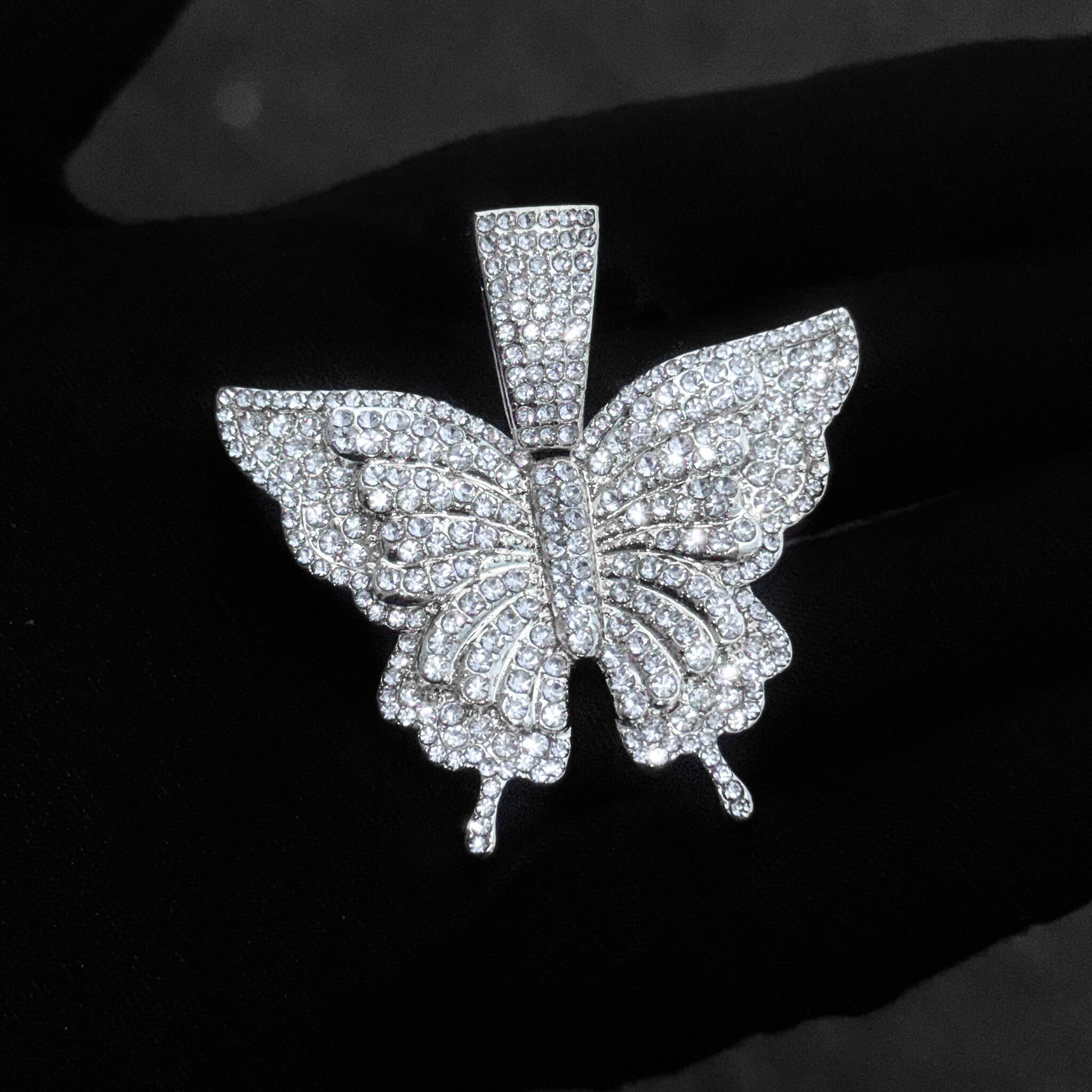 Detailed close-up of silver iced-out butterfly pendant covered in sparkling crystals for women.