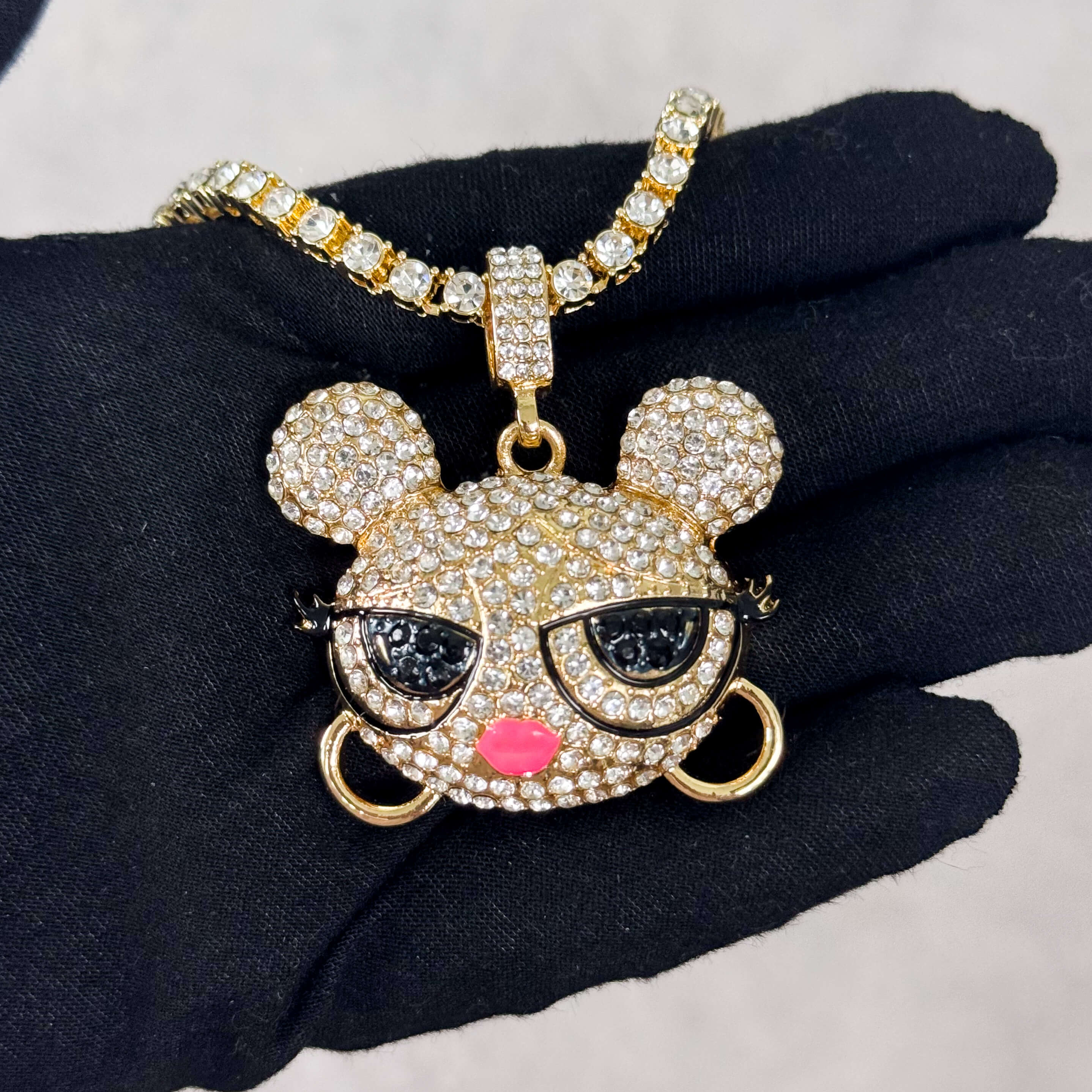 Gold Iced Out Baddie Doll Pendant with Tennis Chain held in hand, fully iced CZ doll charm.
