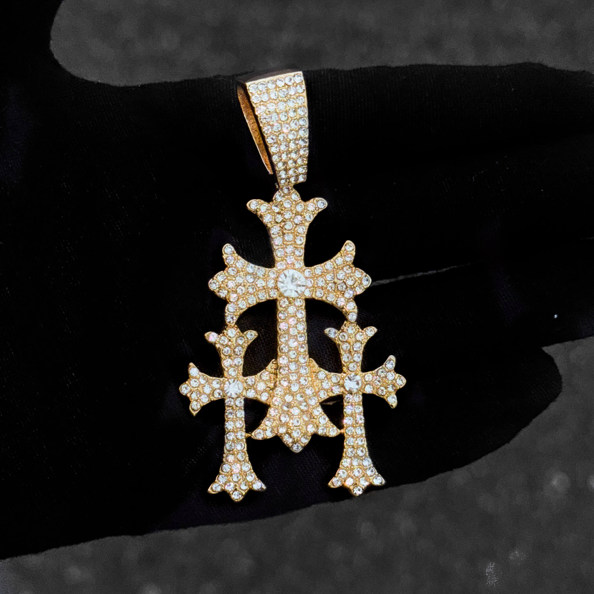Close-up of men’s gold 40mm iced-out cross pendant featuring clustered round stones.