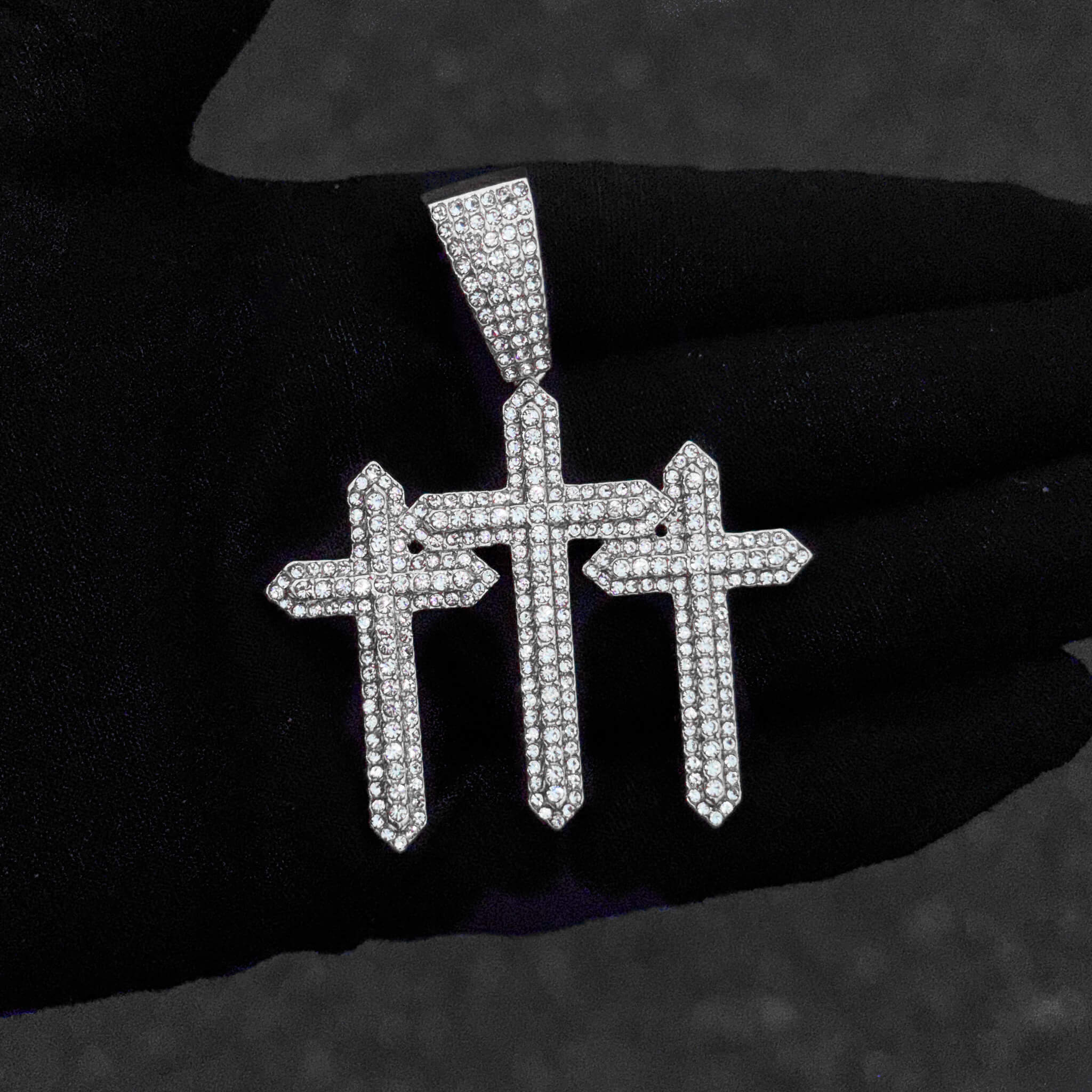 Detailed close-up of silver 53mm iced-out triple cross pendant covered in sparkling stones.
