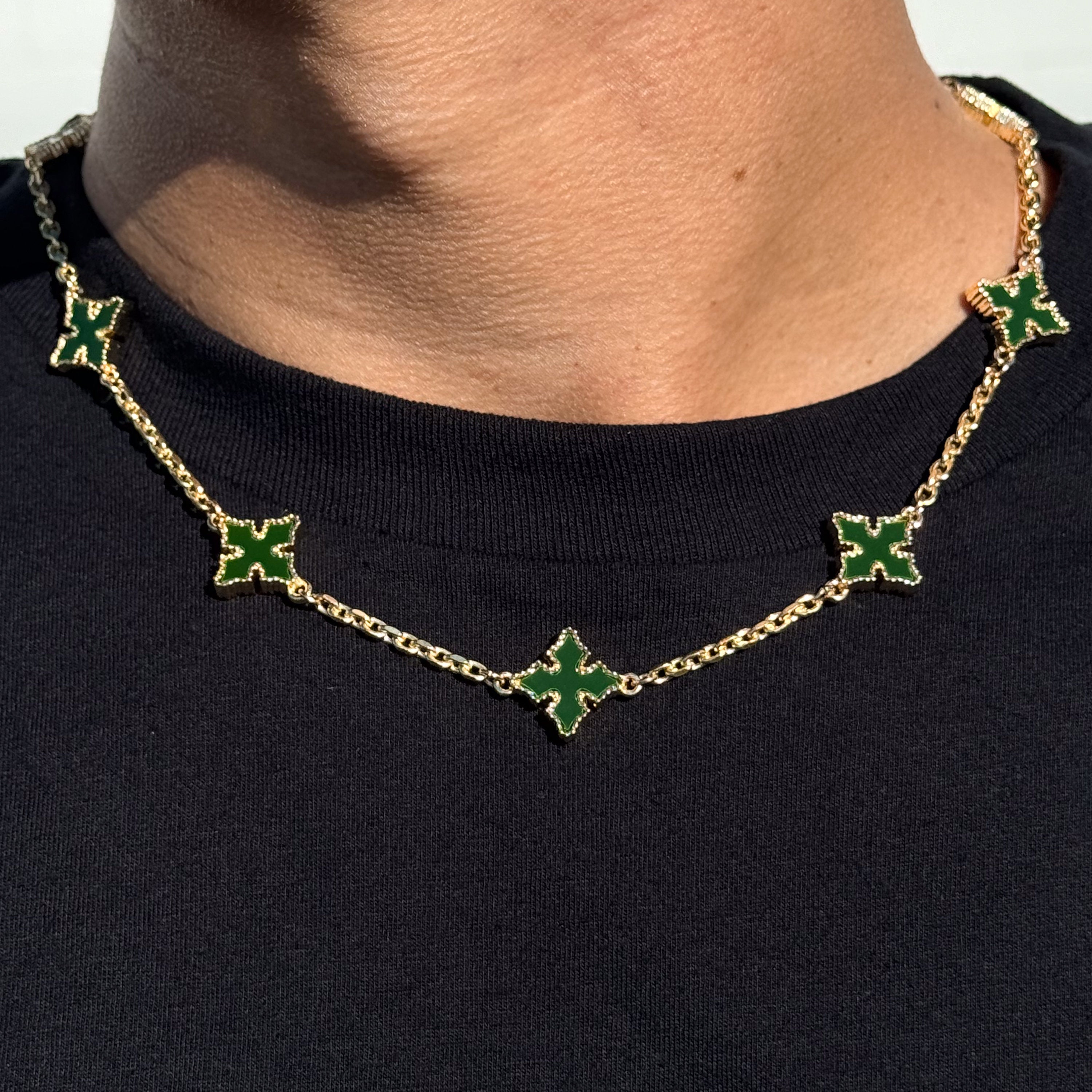Close-up of Multi Cross Chrome Inspired Chain in green and gold, worn on neck with black shirt.