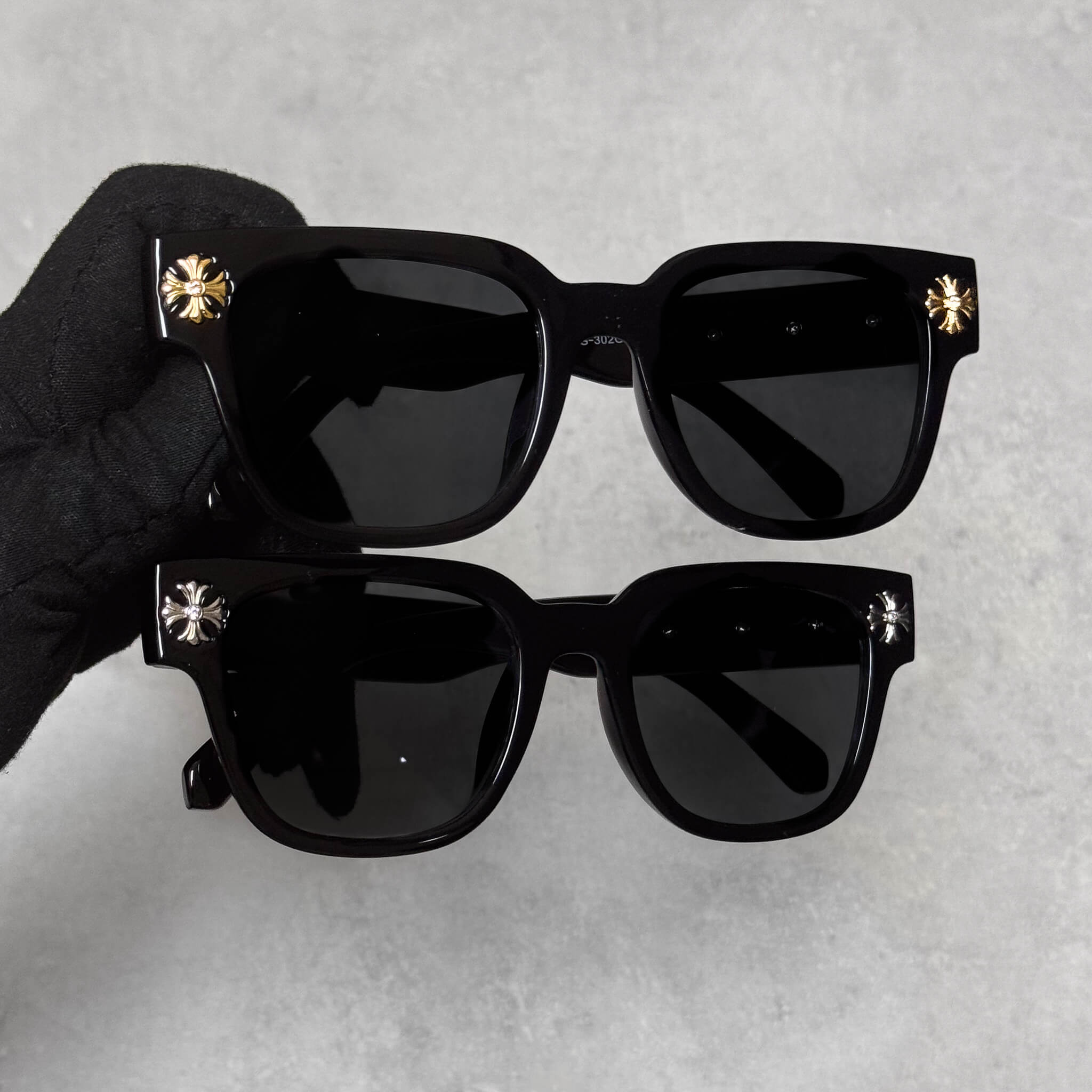 Black Cross Chrome Inspired Sunglasses with dark lenses and gold and silver metal cross accents on corners.